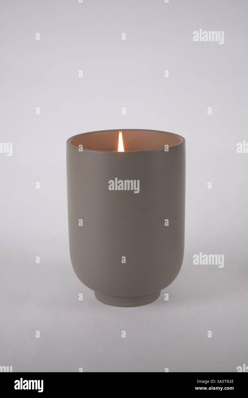 Vaso cilindrico grigio in ceramica con candela profumata in fiamme Foto Stock