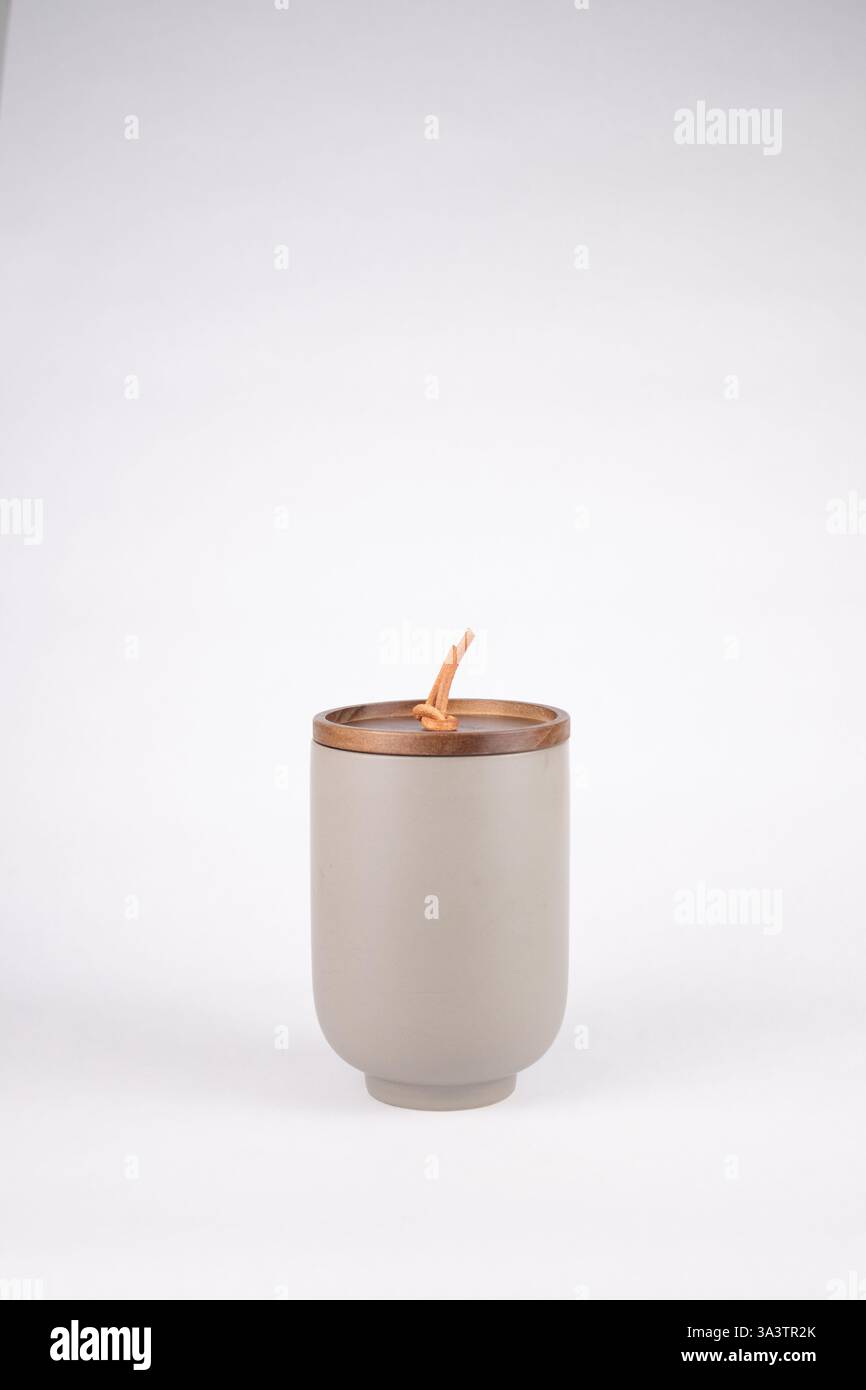 Vaso cilindrico grigio in ceramica con candela profumata e coperchio in legno con rivestimento in pelle Foto Stock