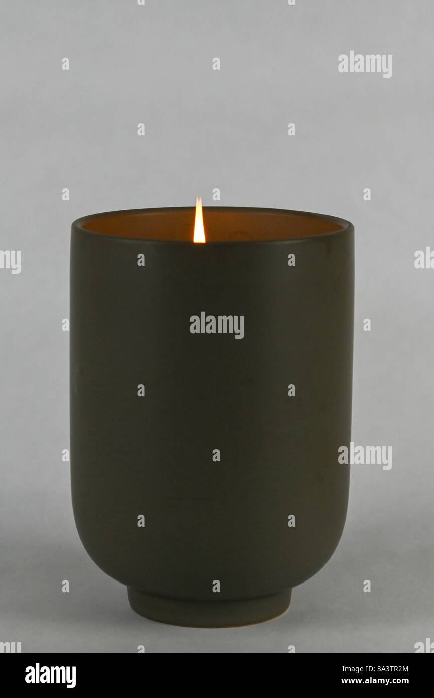Vaso cilindrico grigio in ceramica con candela profumata in fiamme Foto Stock