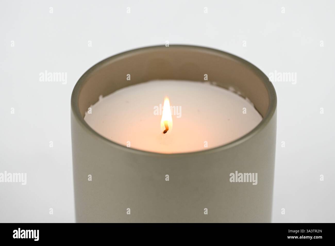 Vaso cilindrico grigio in ceramica con candela profumata in fiamme Foto Stock