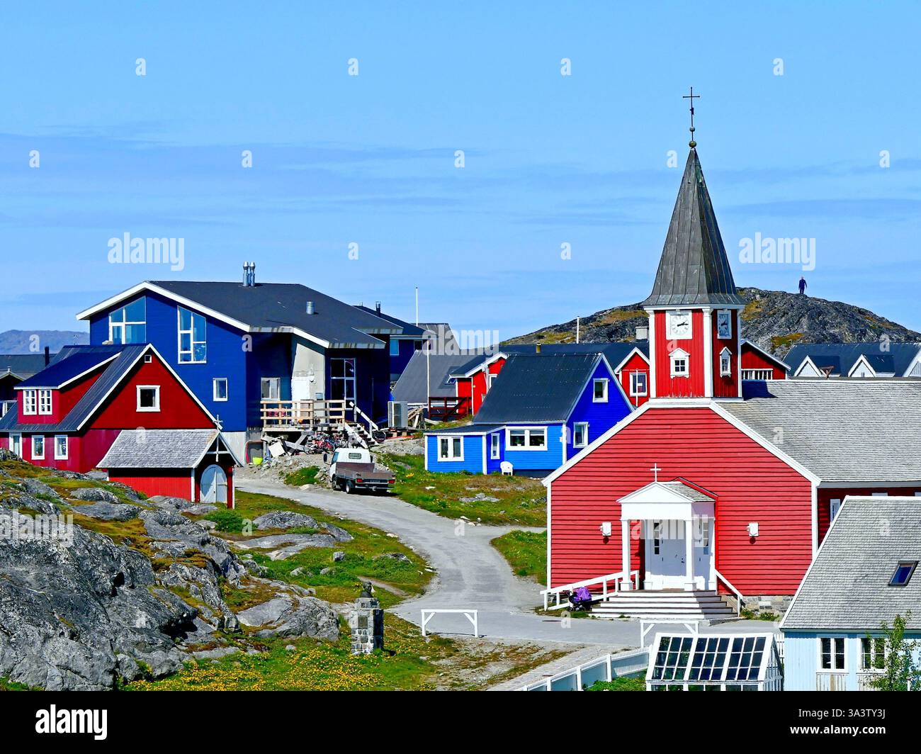 Paesaggio urbano panoramico con edifici residenziali multicolori e una chiesa in legno rosso con un campanile nel cuore della vecchia Nuuk, la capitale della Groenlandia Foto Stock