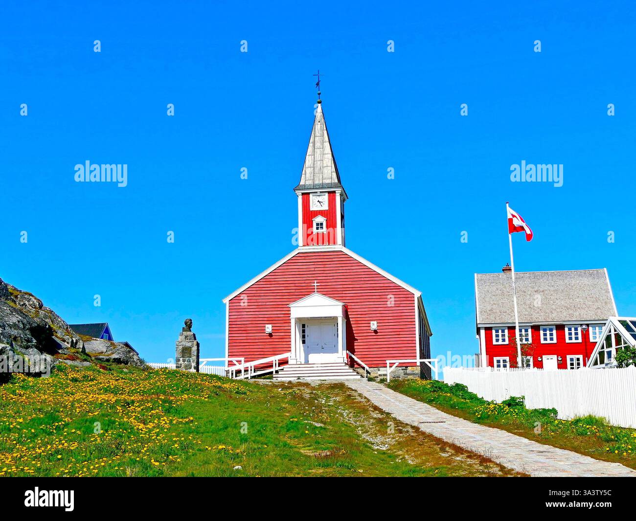 Paesaggio contrastante con chiesa luterana in legno rosso su pendio verde contro cielo azzurro nuvoloso in una soleggiata giornata estiva a Nuuk, la capitale di Greenla Foto Stock