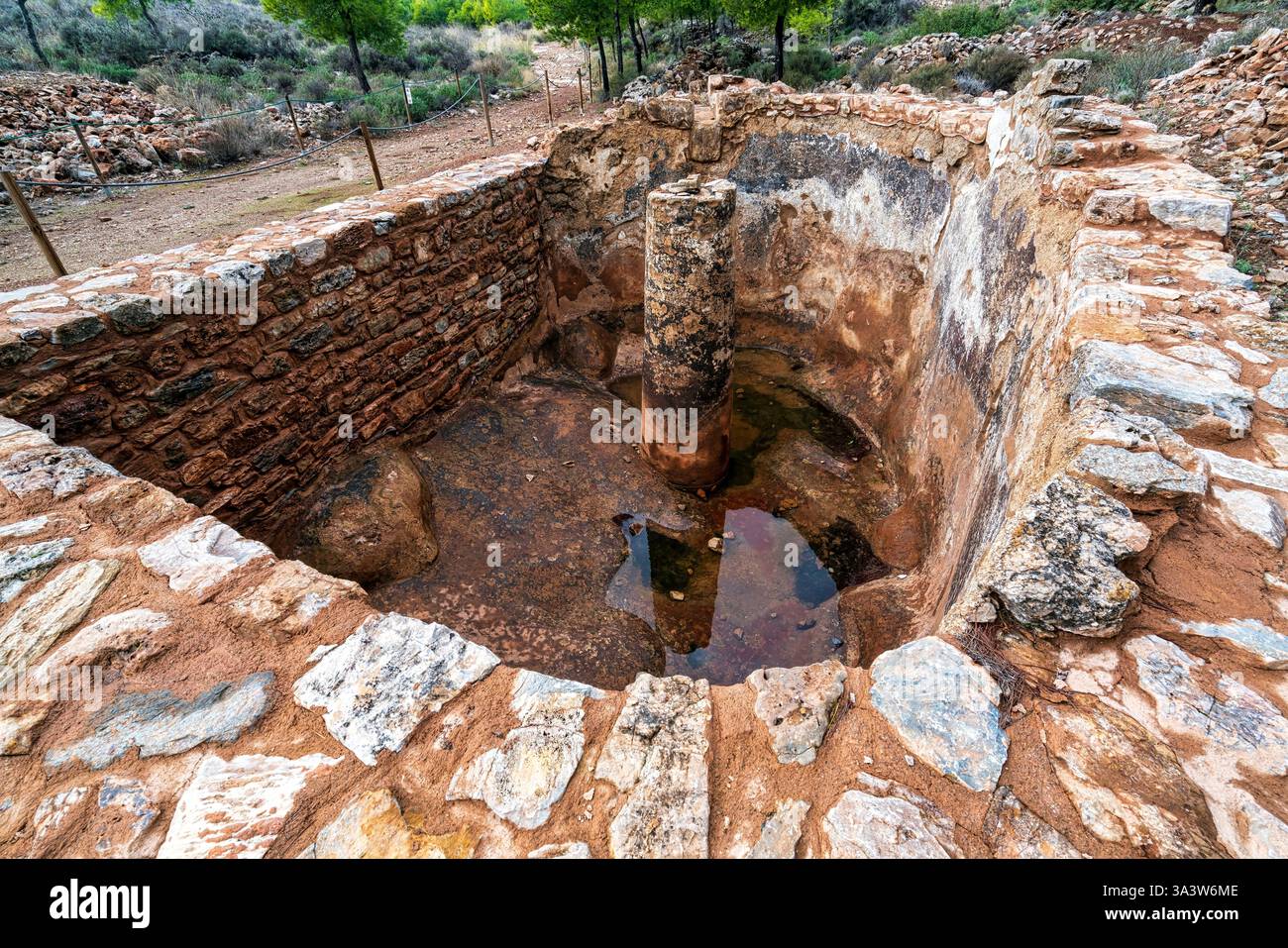 Antico pozzo di lavaggio del minerale costruito in pietra dalle miniere d'argento di Lavrion in Grecia, caratterizzato da una colonna centrale e da un bacino pieno d'acqua. Foto Stock