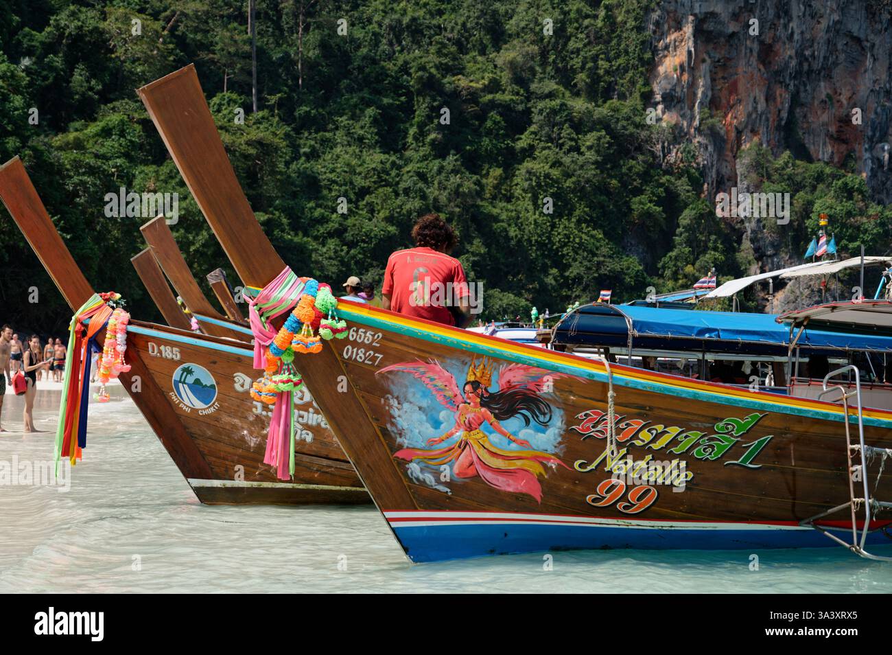 Il giovane barcaiolo siede su una barca a coda lunga decorata, aspettando i turisti sulla riva del Parco delle Scimmie di Dabizha Foto Stock
