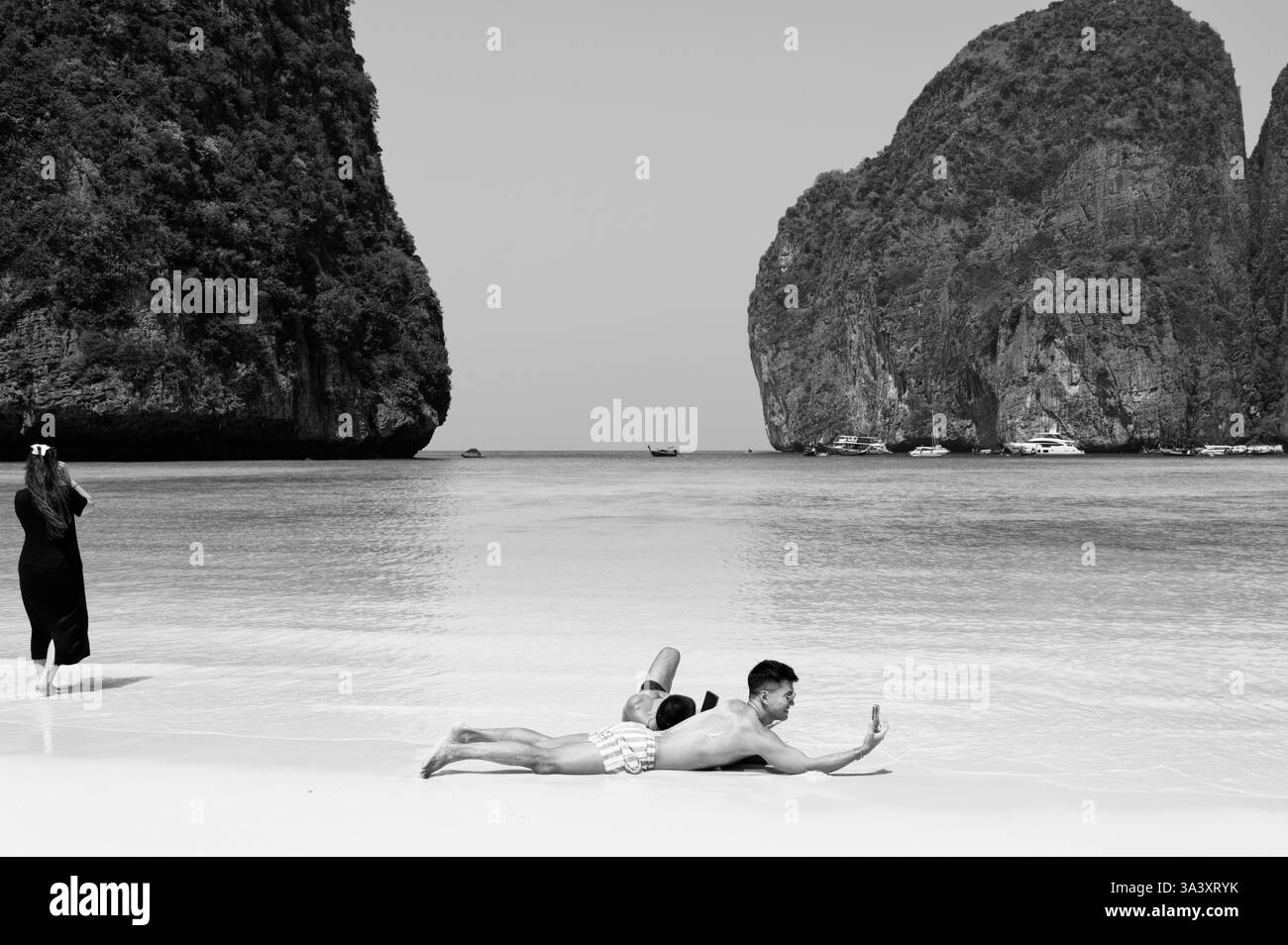 Un paio di salotti sulla riva di Maya Bay, mentre un altro visitatore ammira il panorama Foto Stock