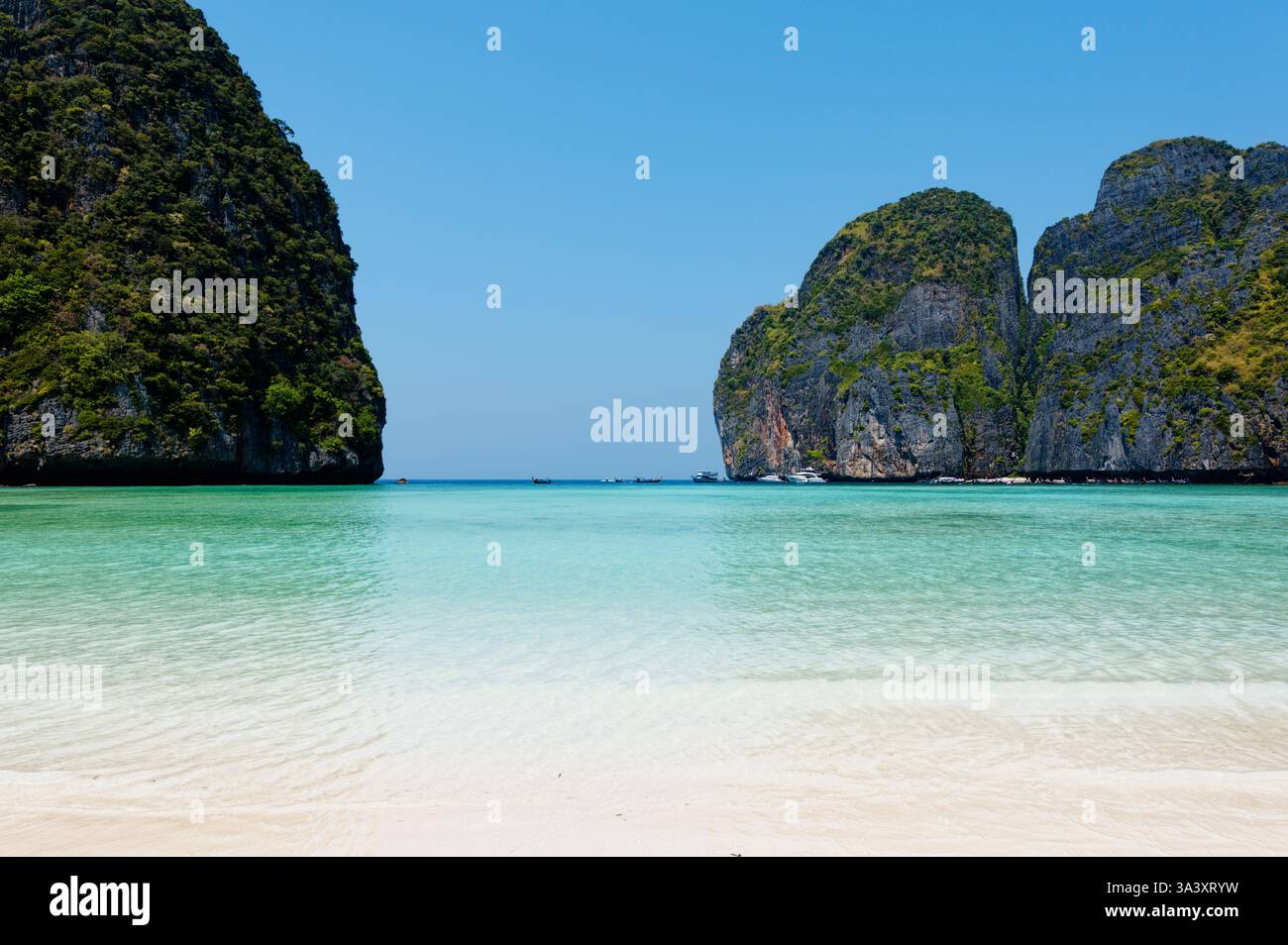 Le limpide acque turchesi si estendono verso le torreggianti scogliere calcaree di Maya Bay Foto Stock
