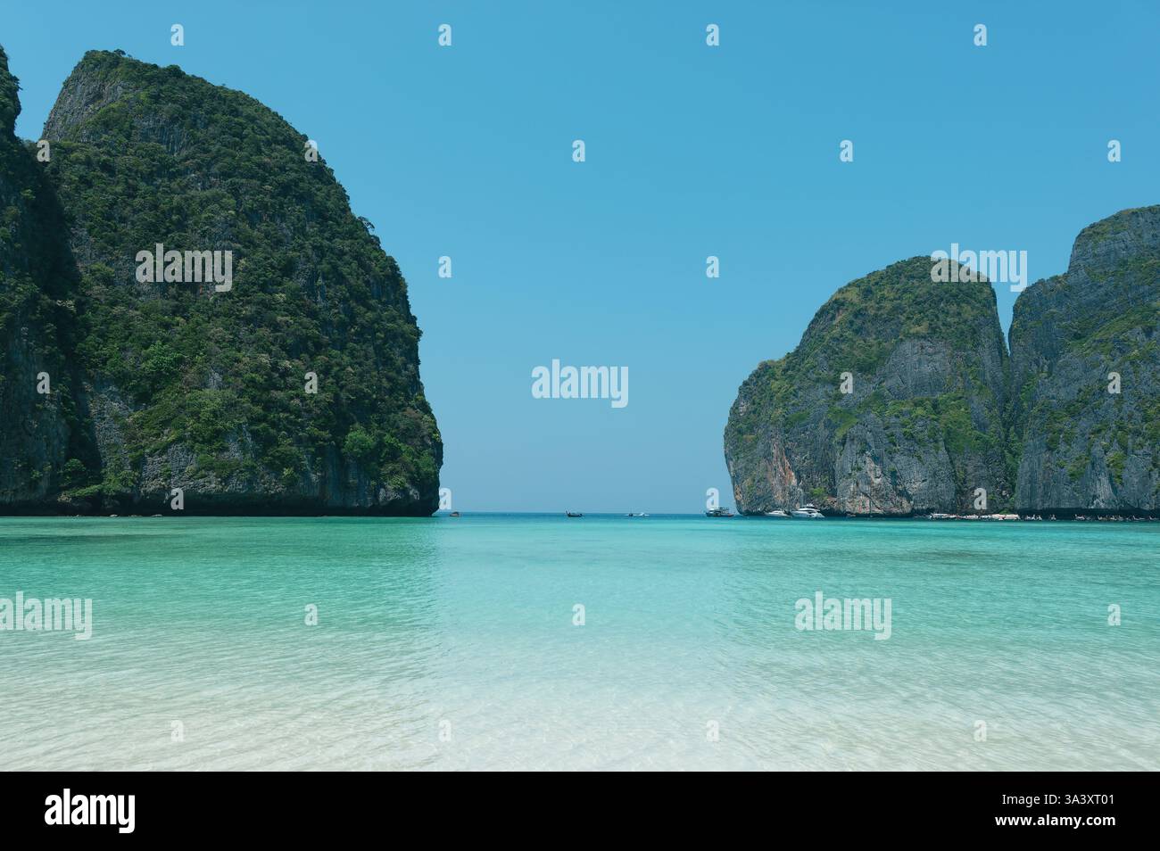 Le limpide acque turchesi si estendono verso le torreggianti scogliere calcaree di Maya Bay Foto Stock