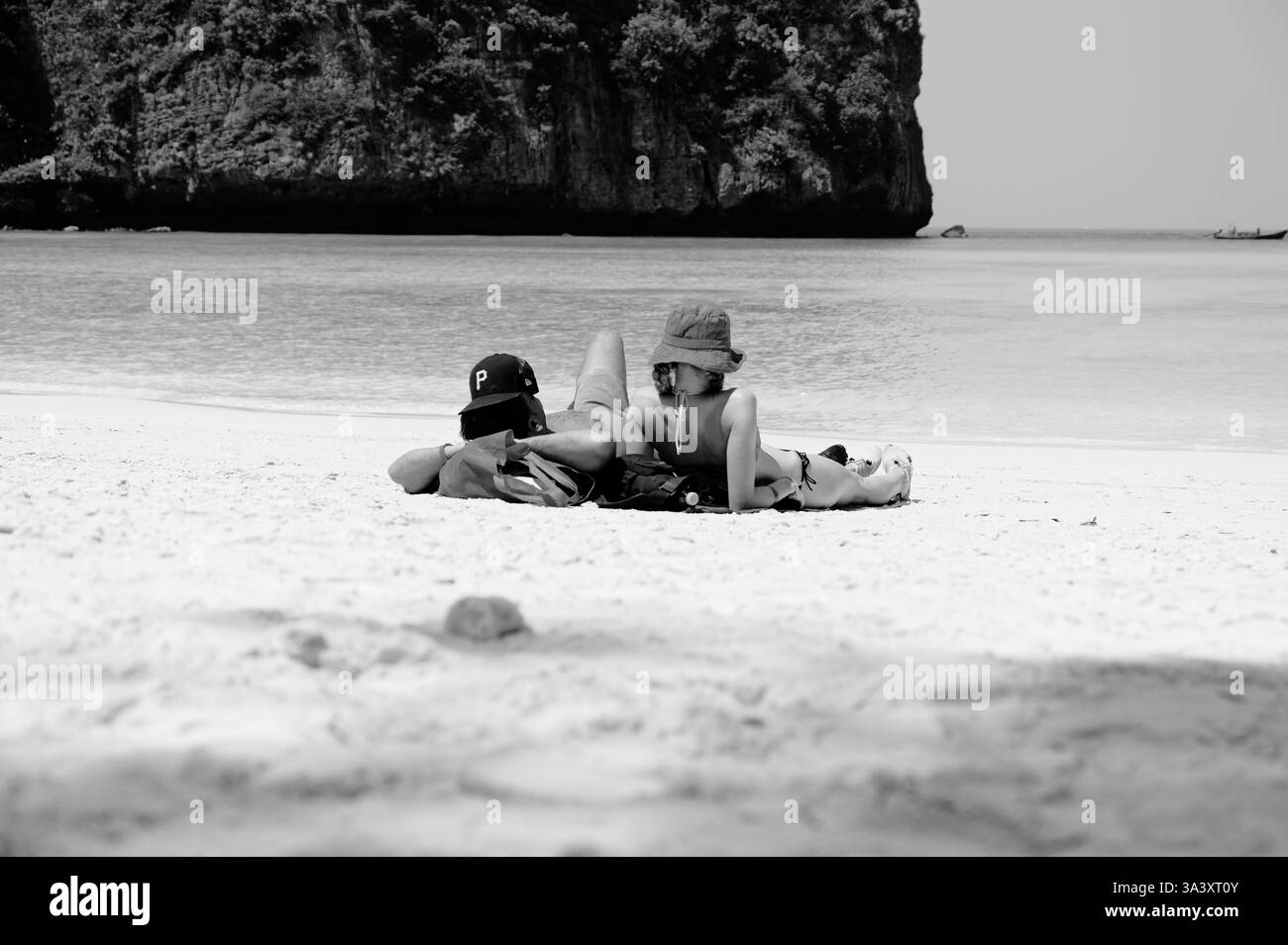 Un paio si snoda sulle sabbie morbide di Maya Bay, osservando l'oceano calmo Foto Stock