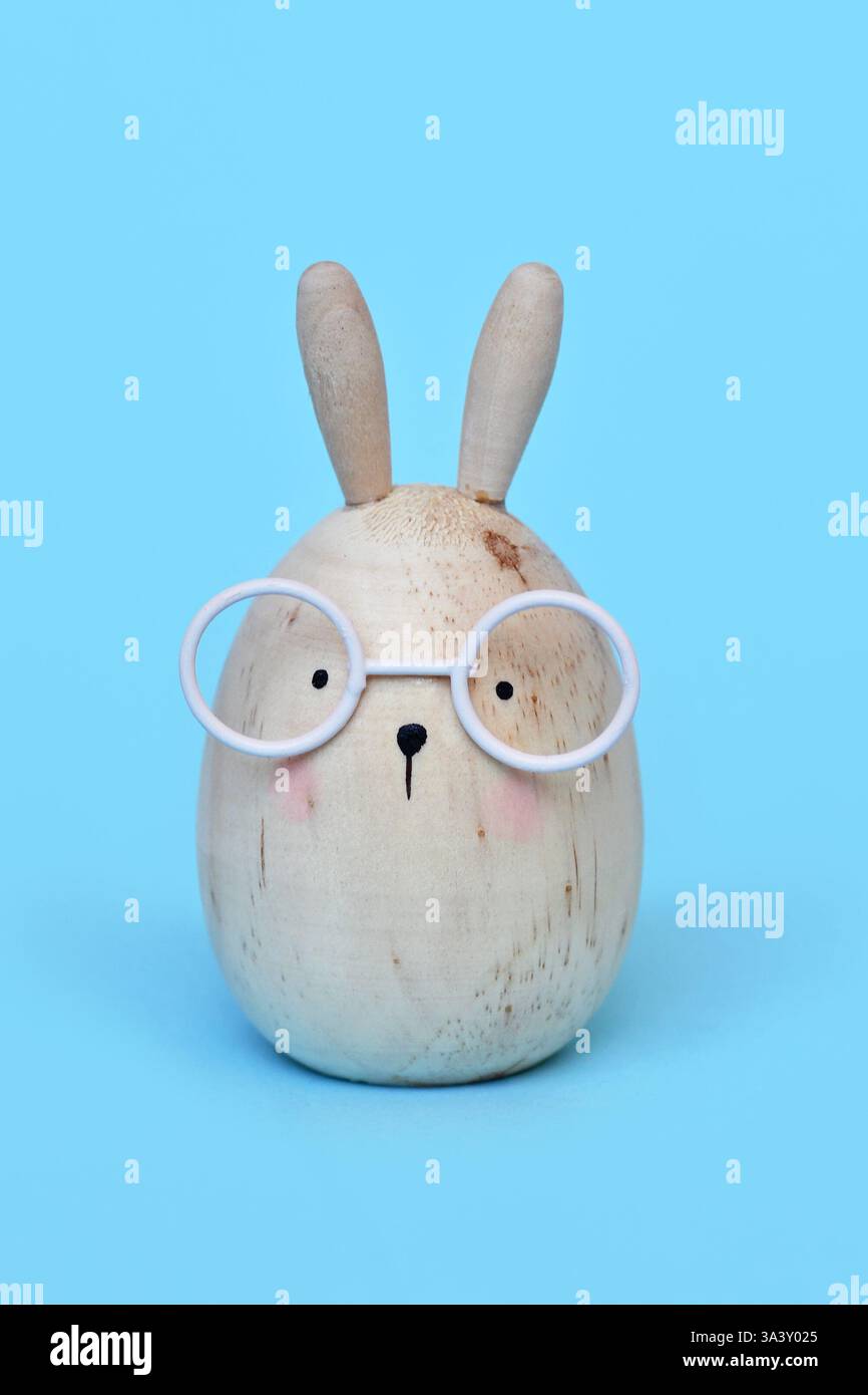 Simpatico simpatico coniglietto pasquale a forma di uovo con bicchieri su sfondo blu Foto Stock