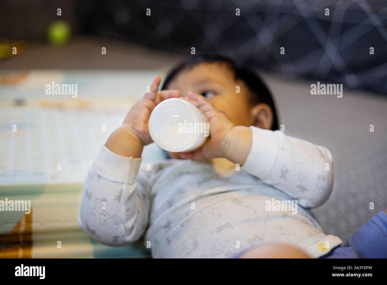 Il bimbo beve latte nella sala giochi, sfondo per pubblicità e carta da parati nella scena dello stile di vita di cibo e bevande. Foto Stock