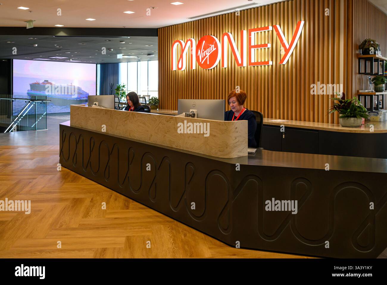 Logo Virgin Money illuminato e area receptione negli uffici della banca a Glasgow, Scozia, Regno Unito Foto Stock