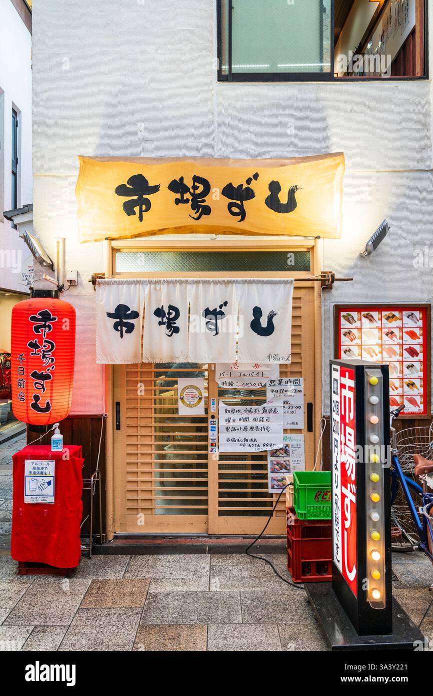 Ingresso ad un piccolo ristorante di sushi a Dotonbori, Osaka. Porte doppie con tendina noren sulla parte superiore. Più chiara sul tavolo, menu sulla parete. Foto Stock