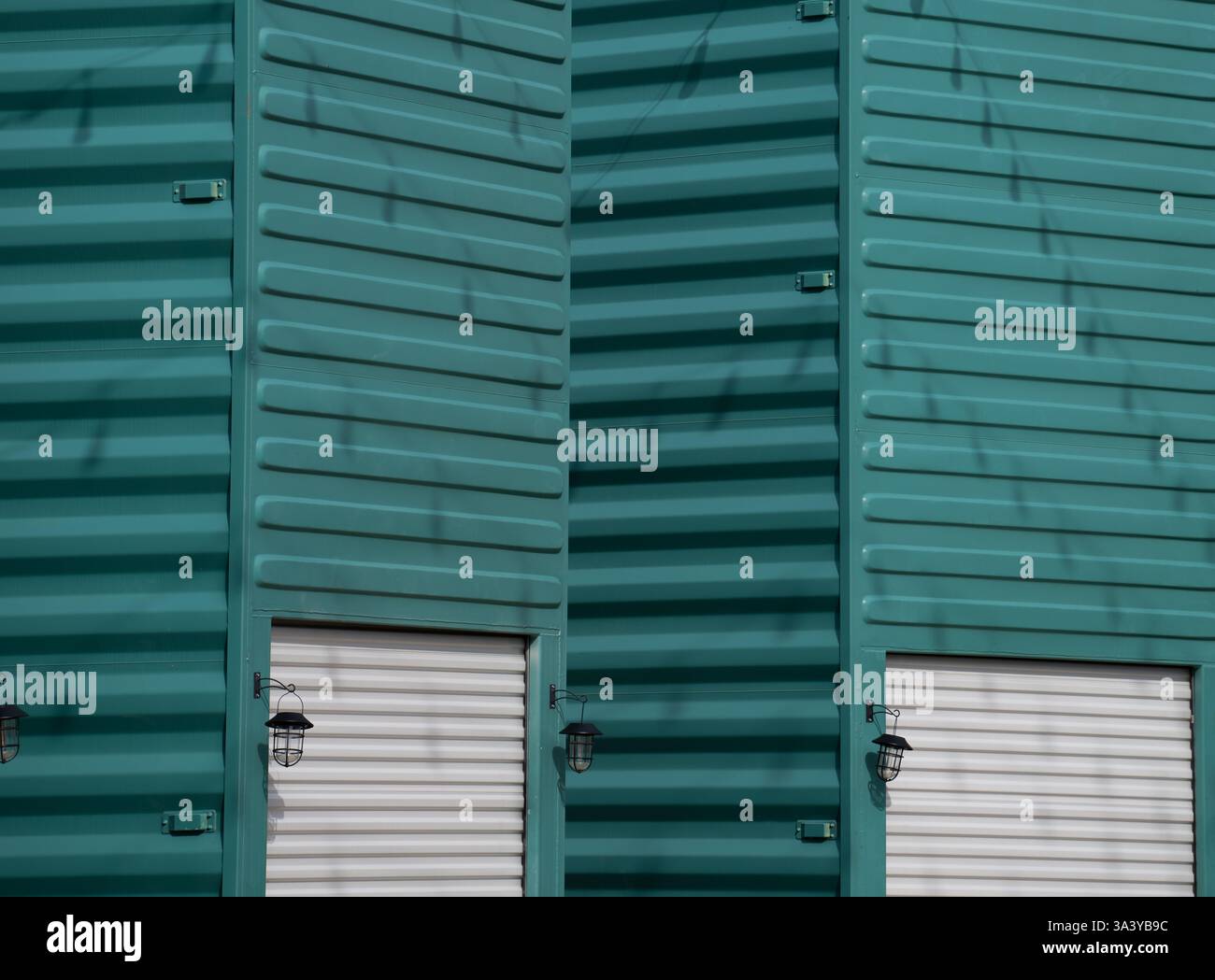 contenitore in metallo all'estremità verticale verniciato turchese con porta del garage in metallo bianco e luce esterna uso creativo di contenitori di tipo orizzontale Foto Stock