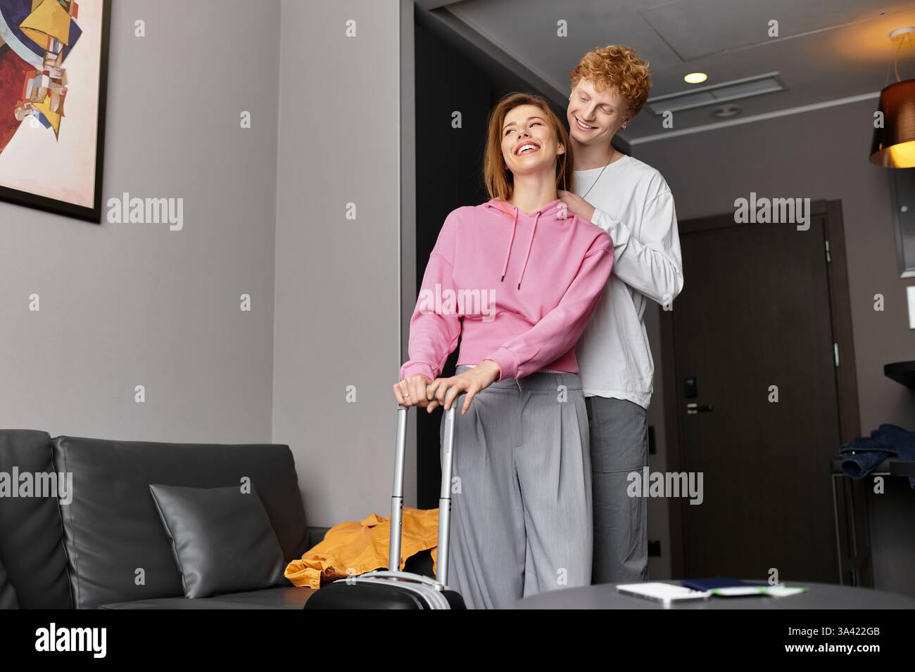 Una coppia felice condivide un momento dolce nella sua camera d'albergo con l'essenziale per il viaggio. Foto Stock