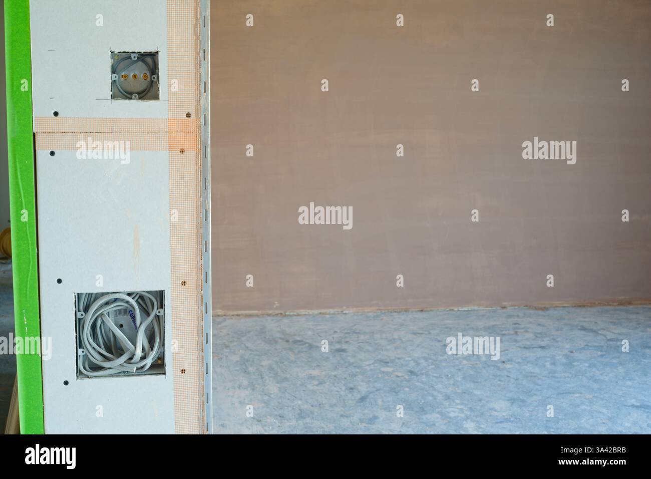 Una nuova sala intonacata con commutazione elettrica, prima installazione degli inserti per cablaggio. Lavori di costruzione rifiniti con una superficie liscia e piatta di intonaco sottile. Foto Stock