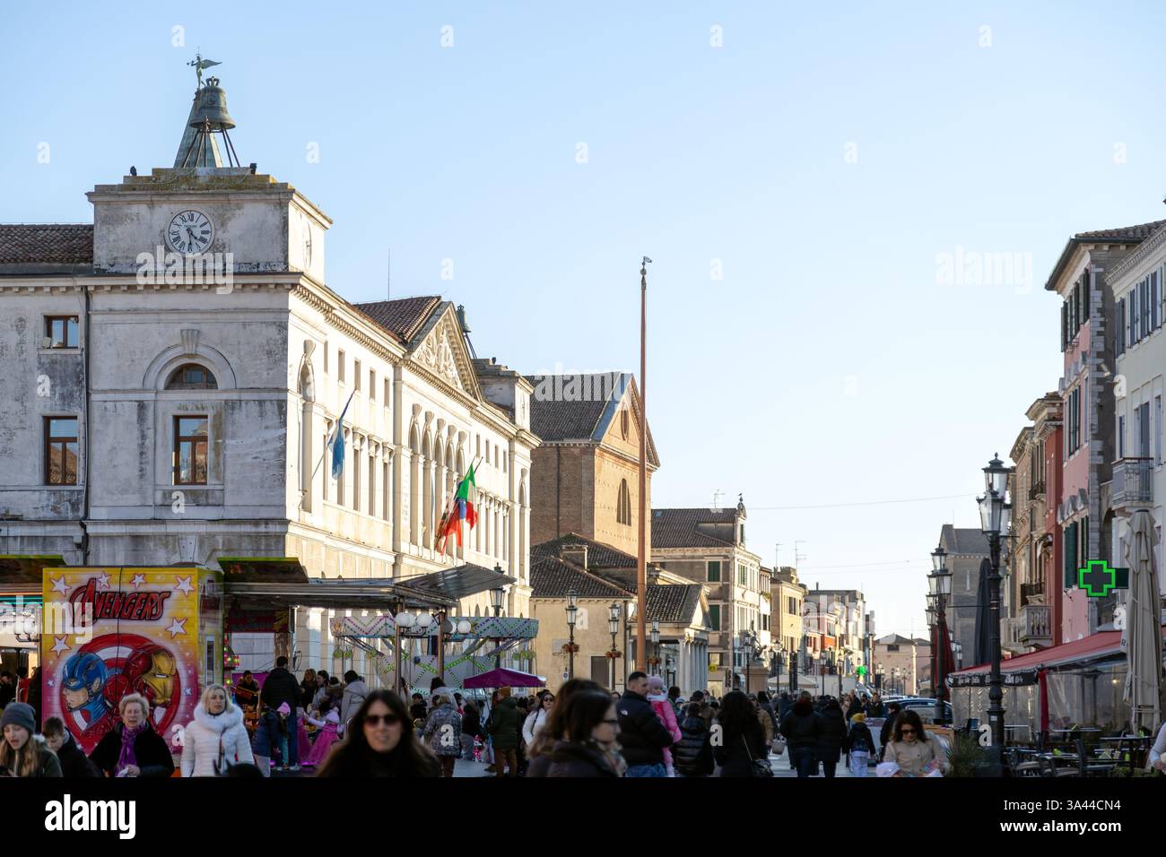 Chioggia, Italia - 3 marzo 2025: Movimentata scena di strada nel centro della città con gente, edifici storici e il Municipio Foto Stock