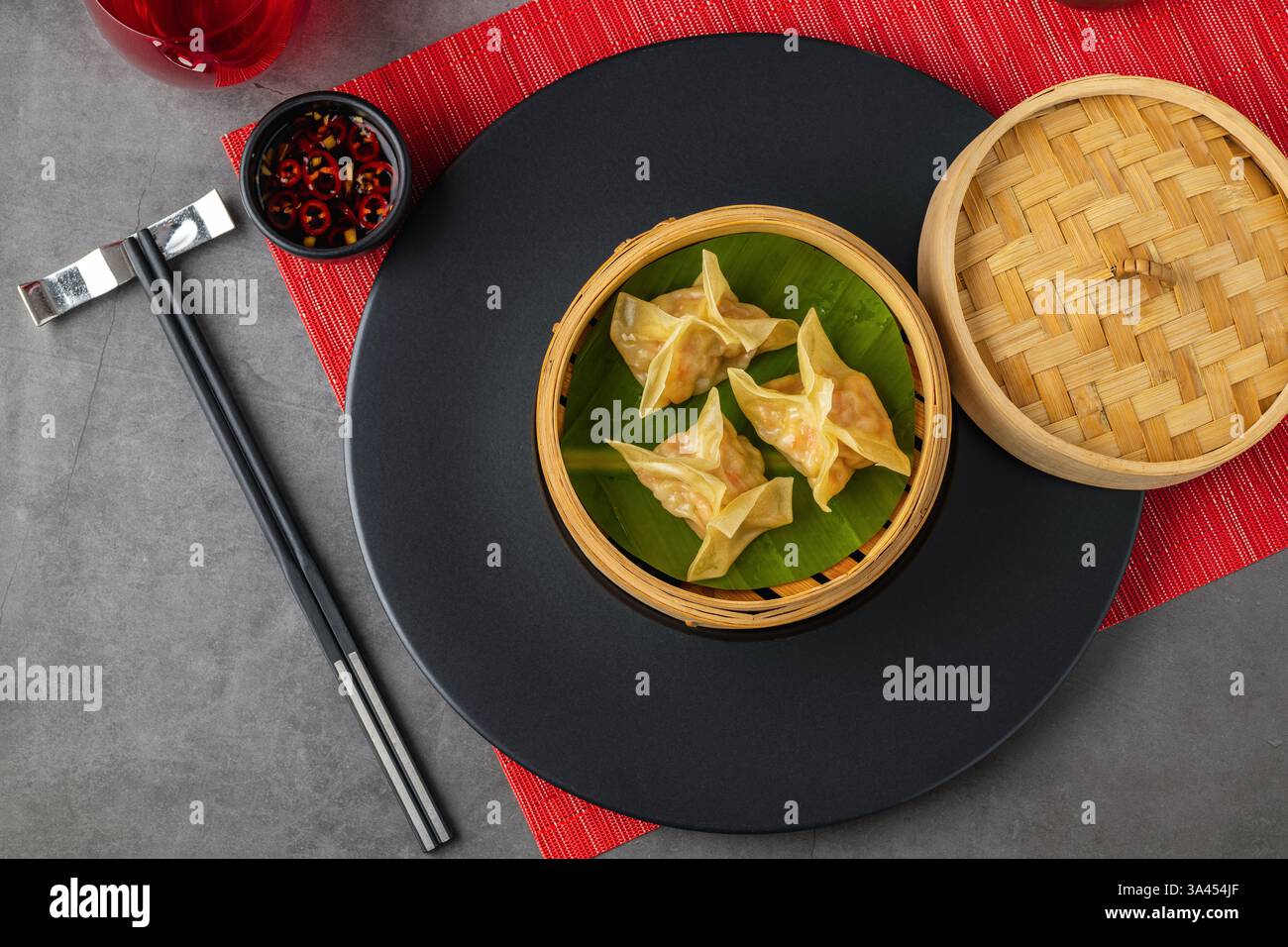 Gnocchi di gamberi al vapore in una vaporiera di bambù con foglia di banana, serviti con salsa di soia al peperoncino Foto Stock