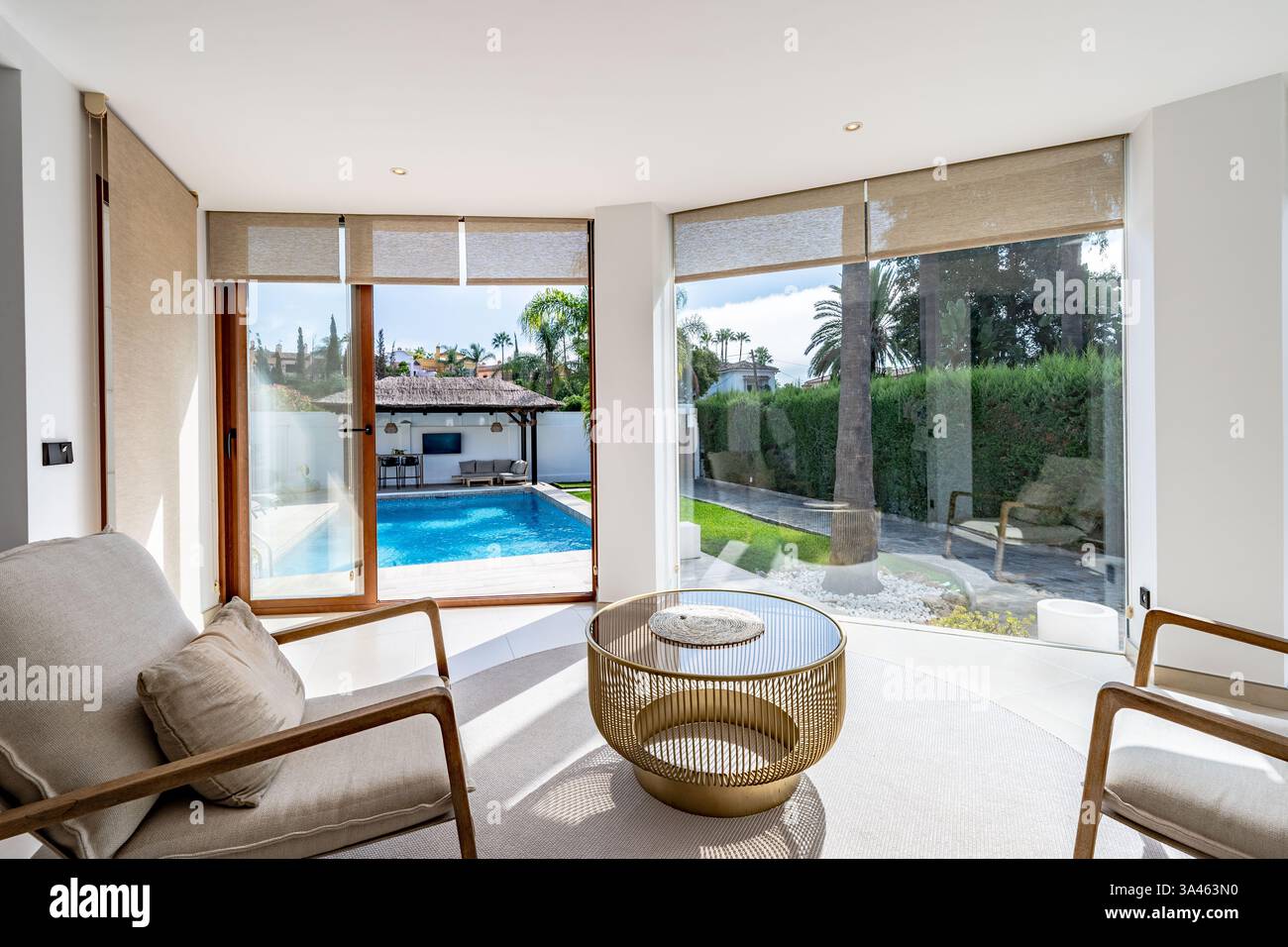 Un'immagine ravvicinata di un soggiorno con finestre di vetro che si affacciano sulla piscina privata nel giardino di lussuose ville mediterranee Foto Stock
