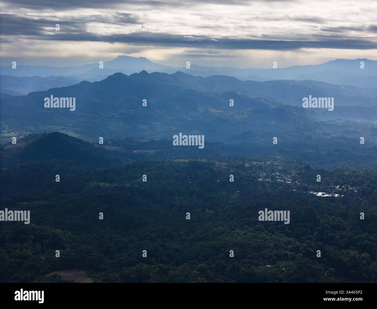 Le montagne nebbiose si estendono in lontananza e si fondono con nuvole basse e luce soffusa del mattino che illuminano il paesaggio. Foto Stock