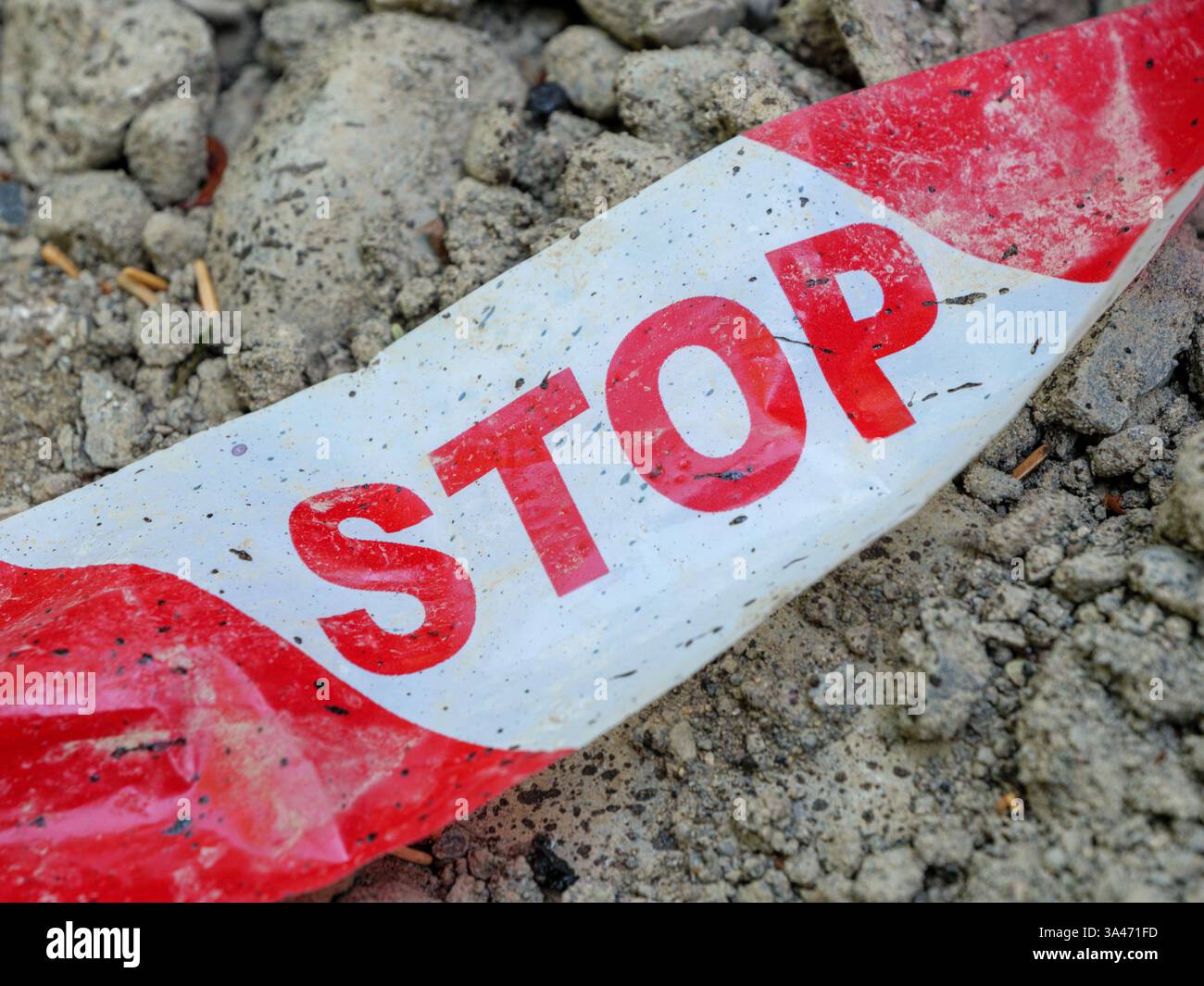 Nastro di sicurezza con avviso DI ARRESTO posizionato su un terreno irregolare in un cantiere edile Foto Stock