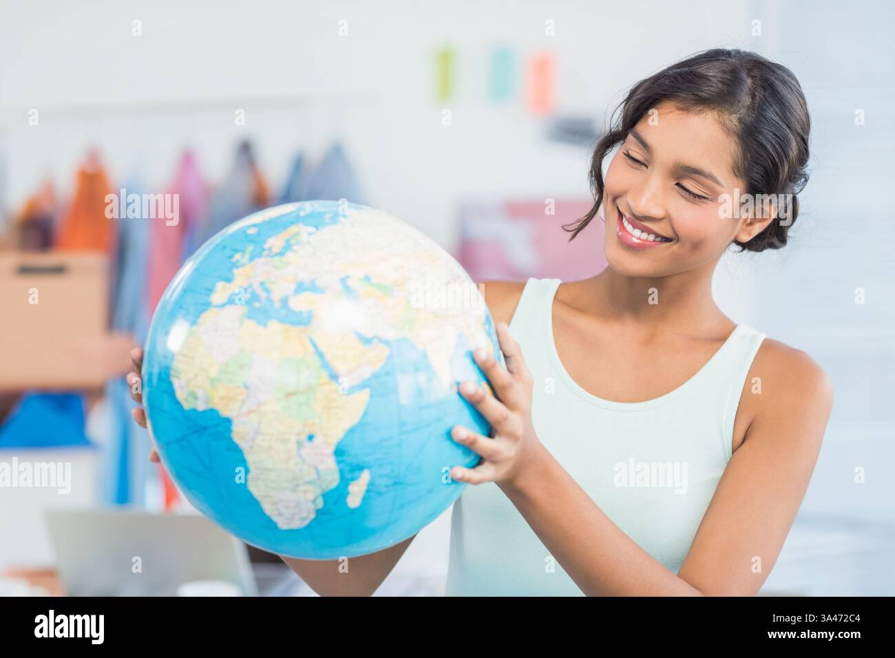 Donna sorridente che tiene il globo in carica, esplorando opportunità commerciali globali Foto Stock