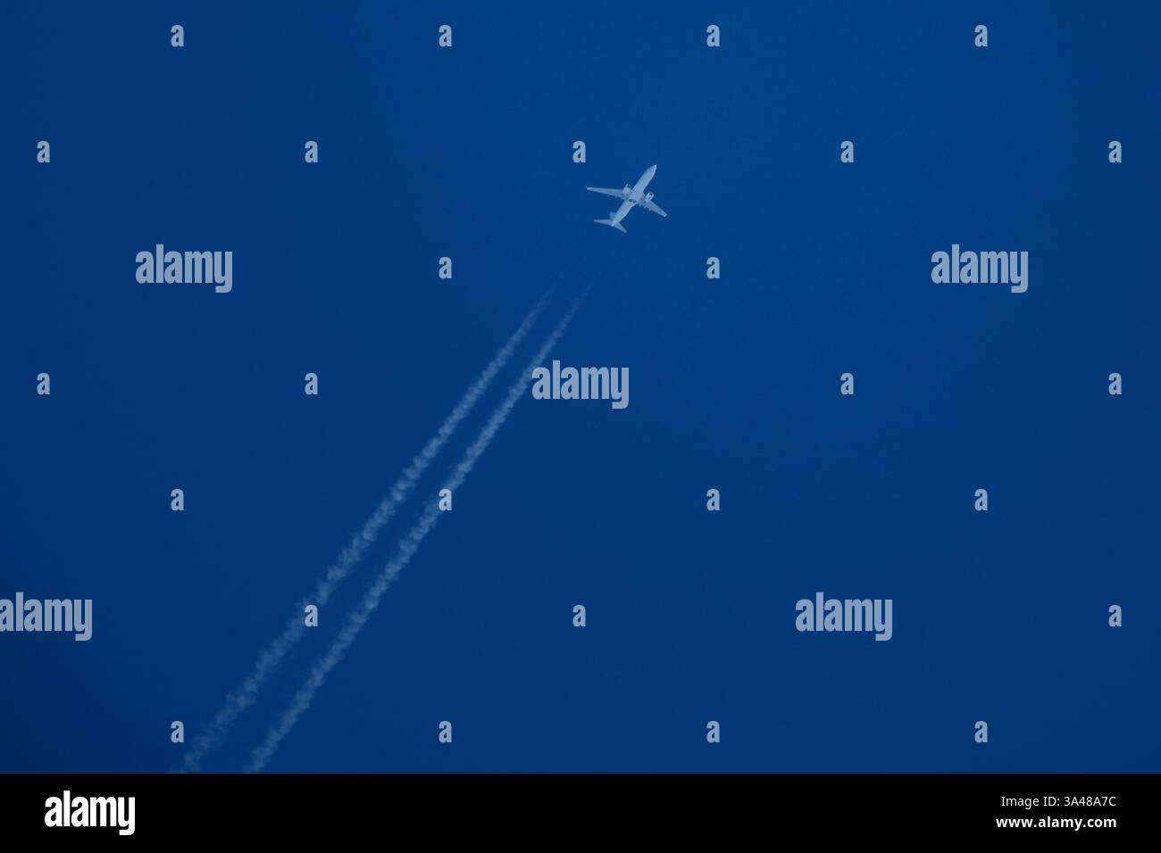Aeroplano nel cielo blu con il contrail bianco Foto Stock
