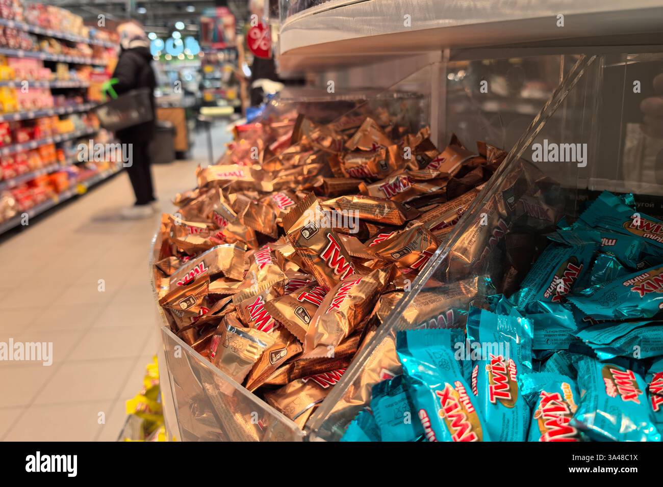 Bobruisk, Bielorussia - 2 marzo 2025: Gli avvolgimenti di caramelle brillano nelle tonalità dell'oro e del blu, invitando gli acquirenti in un vivace corridoio della spesa. Foto Stock