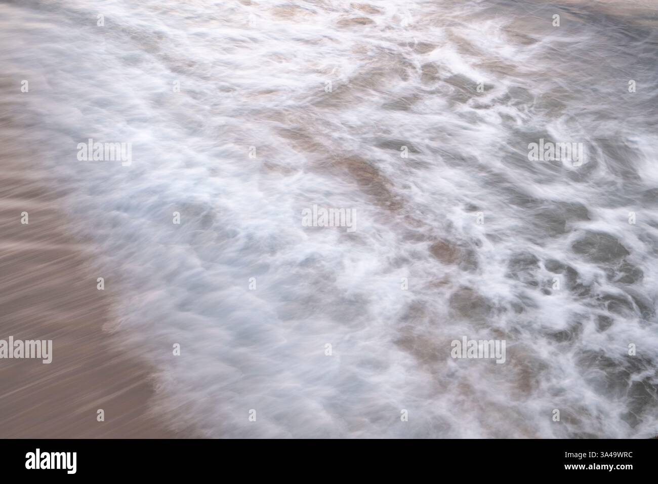 Onde astratte a lunga esposizione che si infrangono su una spiaggia Foto Stock
