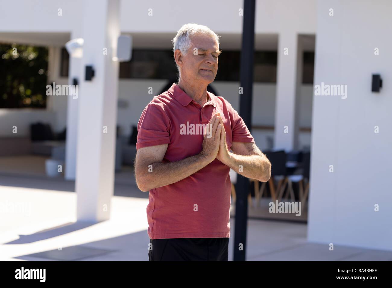 Uomo anziano che meditava a bordo piscina, praticava consapevolezza e relax all'aperto, spazio fotocopie Foto Stock