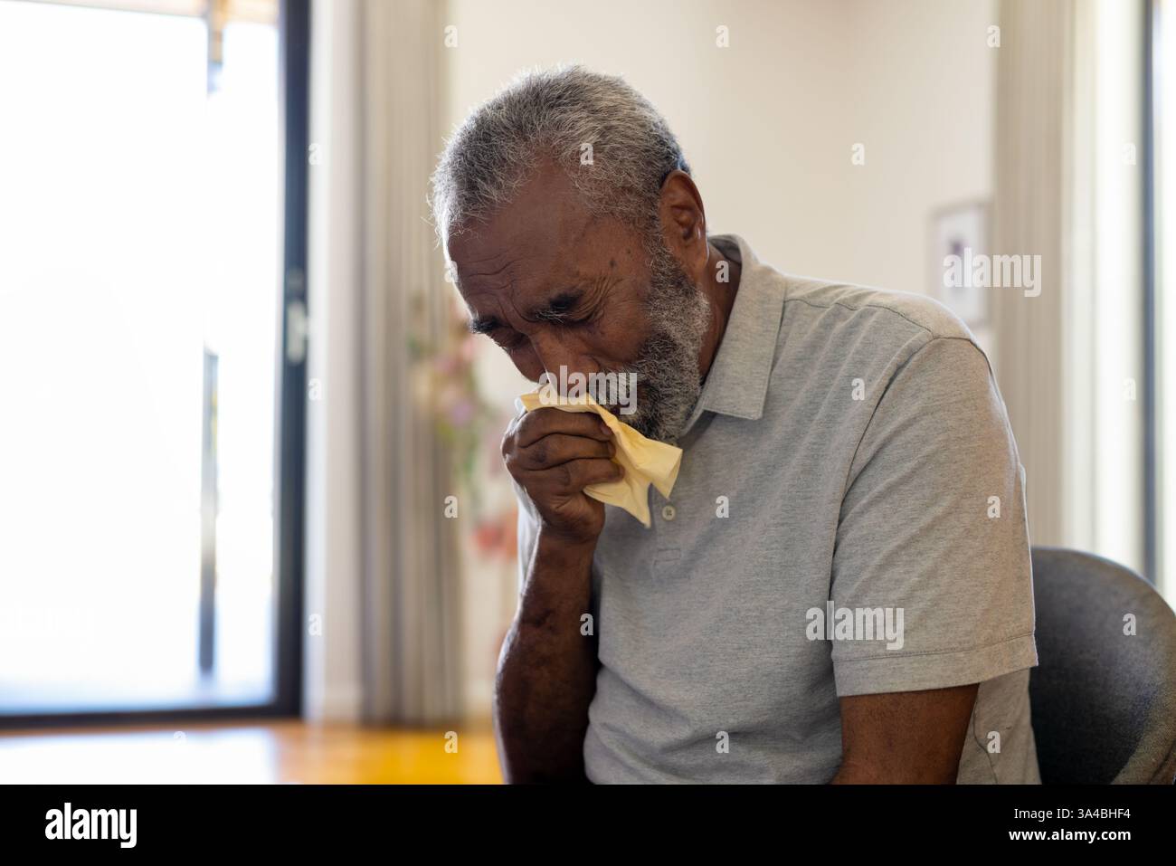 Uomo anziano seduto a casa, che pulisce le lacrime con il tessuto, si sente emotivo, copia lo spazio Foto Stock