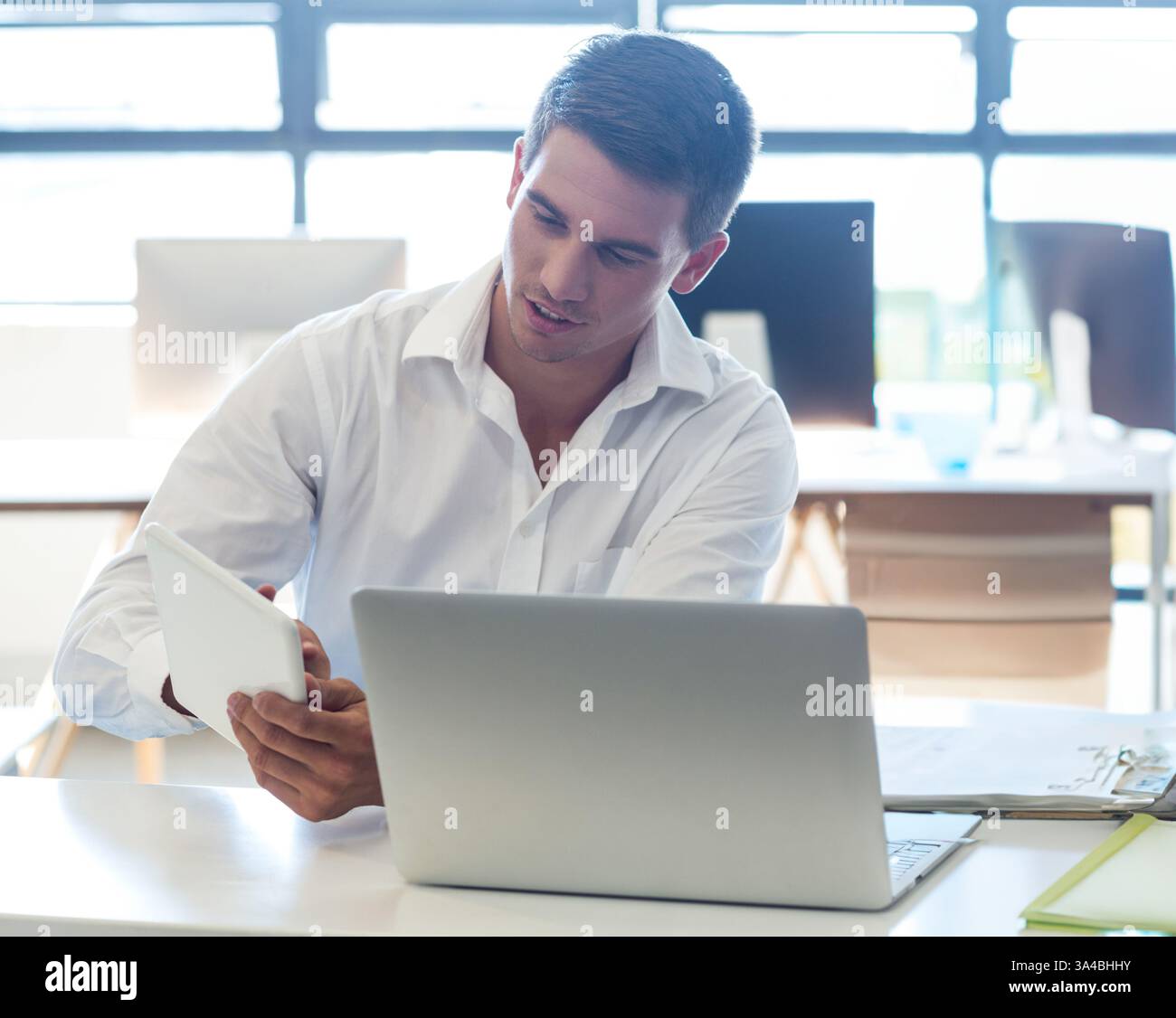 Giovane professionista che utilizza tablet e notebook in un ufficio moderno, concentrandosi sul lavoro e sullo spazio di copia Foto Stock