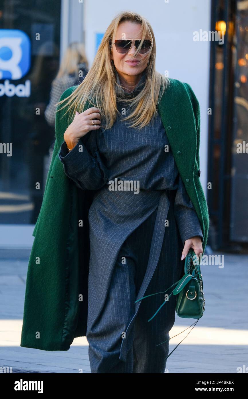 Amanda Holden lascia i Global Studios dopo aver presentato il suo show per la colazione Heart radio con pantaloni grigi, cappotto verde e sandali con listini. Foto Stock