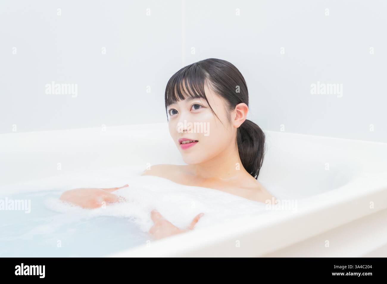 Giovane donna che si immerge in acqua calda nel bagno Foto Stock