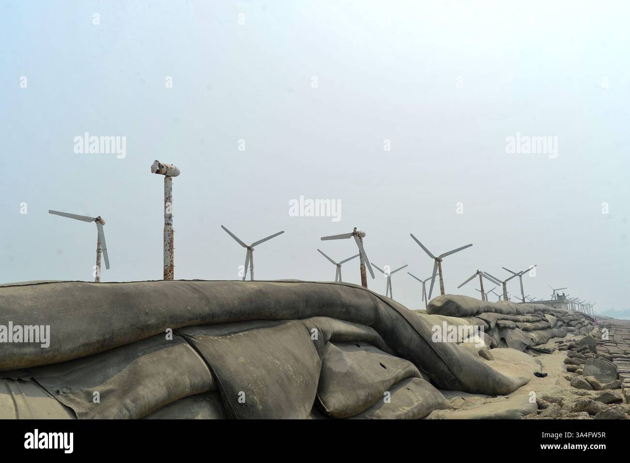 Un tempo simbolo di speranza per l'energia verde, le turbine eoliche arrugginite sull'isola di Kutubdia sono ora abbandonate. Una volta operativa e generatrice di elettricità, sono cadute in rovina, sollevando preoccupazioni per la cattiva gestione e il futuro delle iniziative del Bangladesh in materia di energie rinnovabili. Isola di Kutubdia, Bangladesh. Foto Stock