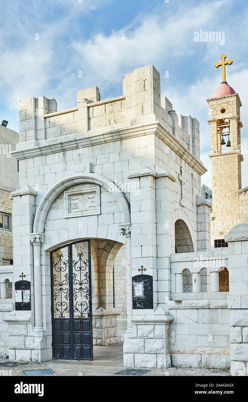 Nazareth, Israele - 15 febbraio 2025: Una vista dettagliata di un ingresso storico dei villaggi, che mostra intricati lavori in pietra, un cancello di ferro e un simbolo religioso Foto Stock