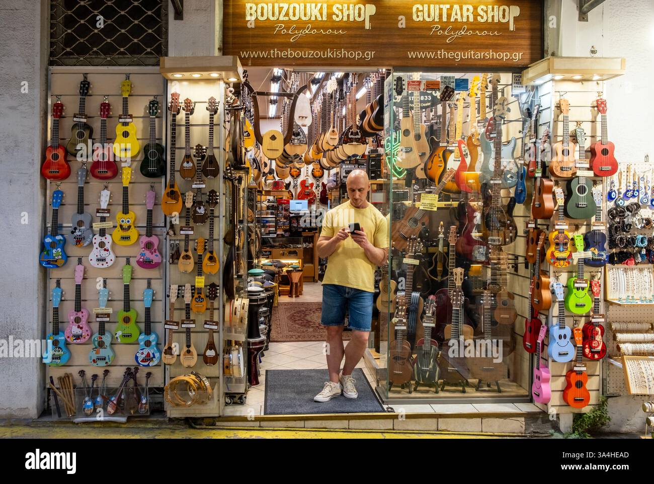 Vista frontale del negozio di chitarre con un uomo all'ingresso di Atene, Grecia Foto Stock