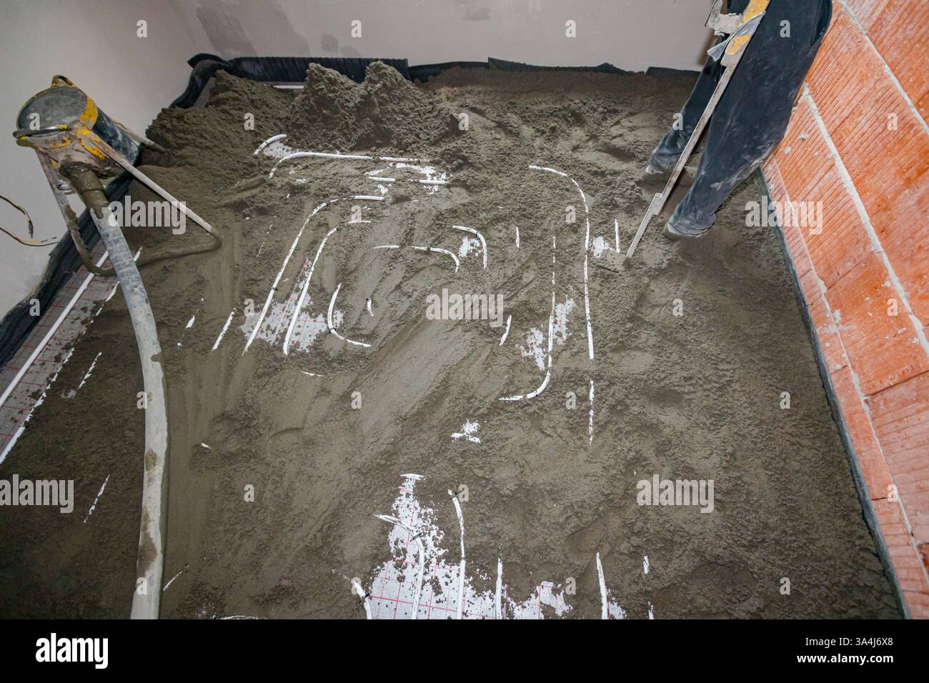 La macchina a pompa getta la miscela di cemento e sabbia, la miscela di massetti semi-asciutti, versare su tubi sottili, sistema di distribuzione per il riscaldamento a pavimento Foto Stock