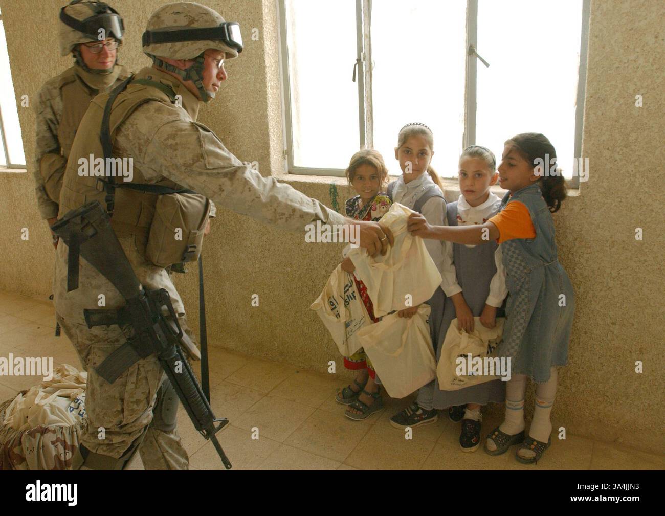 17 settembre 2004; Camp Mahmudiyah, Iraq; i marines del 2nd Battalion, 2nd Marine Regiment, distribuiscono i rifornimenti scolastici ai bambini locali. Un'organizzazione americana, Spirit of America, ha donato i suppies alle scuole irachene. Foto Stock