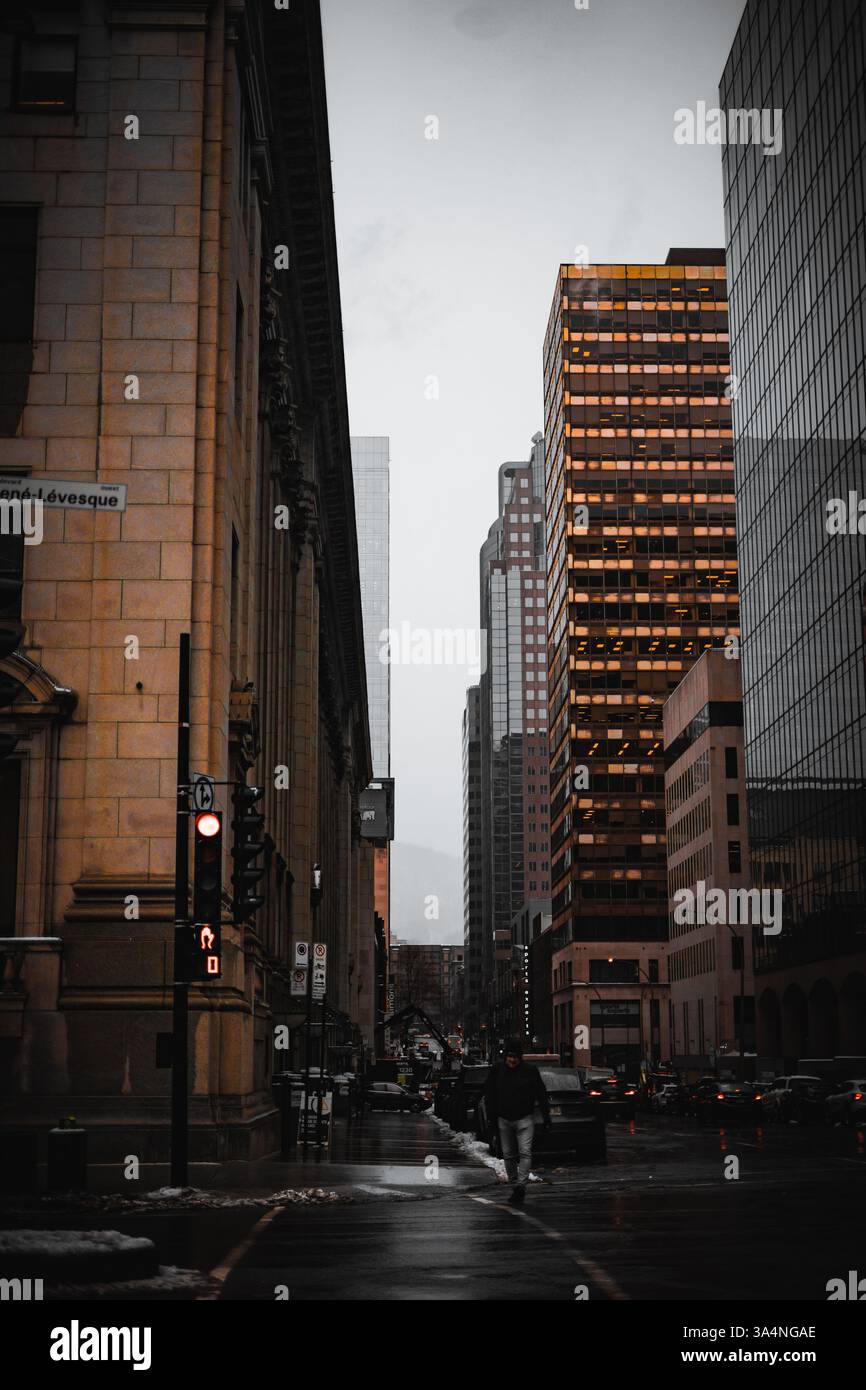 Strada urbana trafficata di sera con semafori e grattacieli, un paesaggio urbano moderno misto a vecchi edifici. Foto Stock