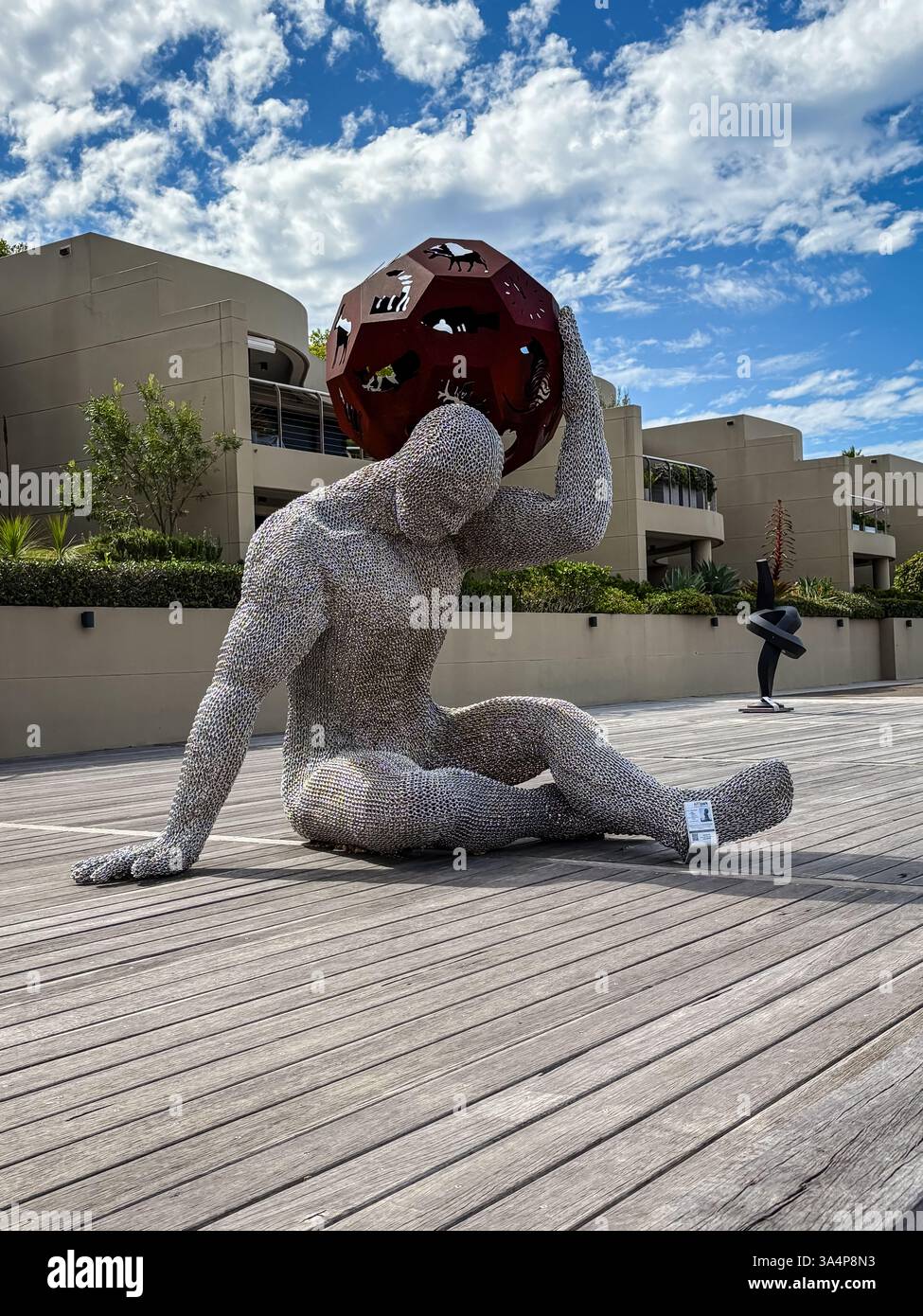 La statua è realizzata in metallo e rete, seduta su un pavimento di legno a Sydney, Australia. La figura sta tenendo una sfera sopra la testa. Foto Stock