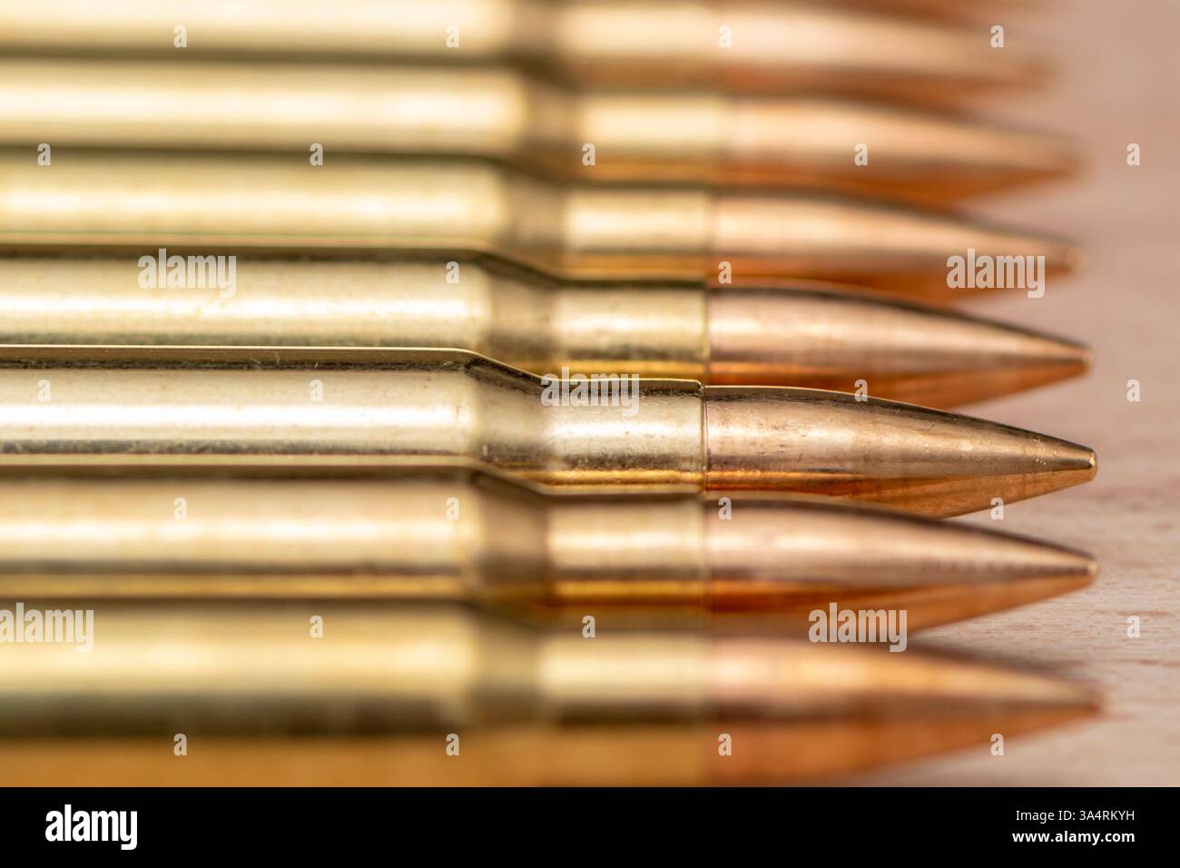 Le cartucce del fucile sono allineate in fila su uno sfondo di legno Foto Stock