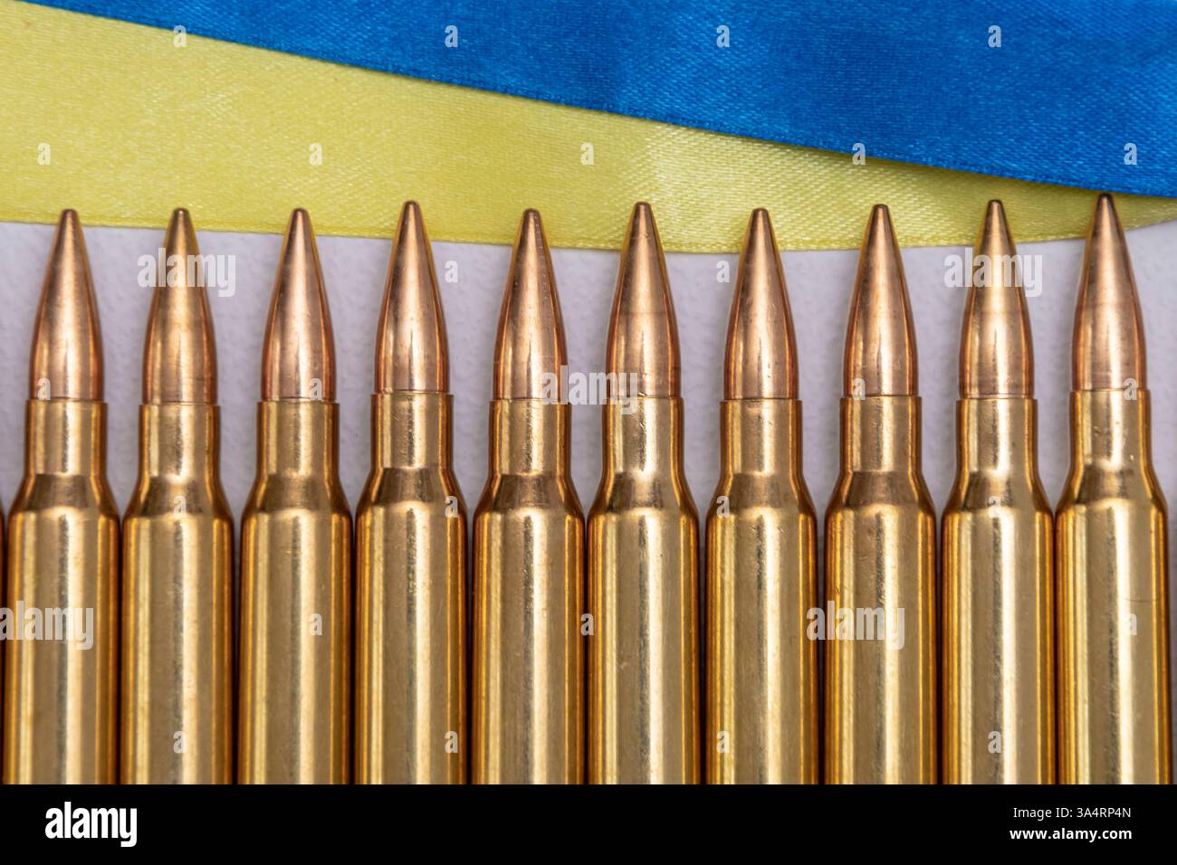 Una fila di cartucce di fucili e la bandiera Ucraina. Foto Stock