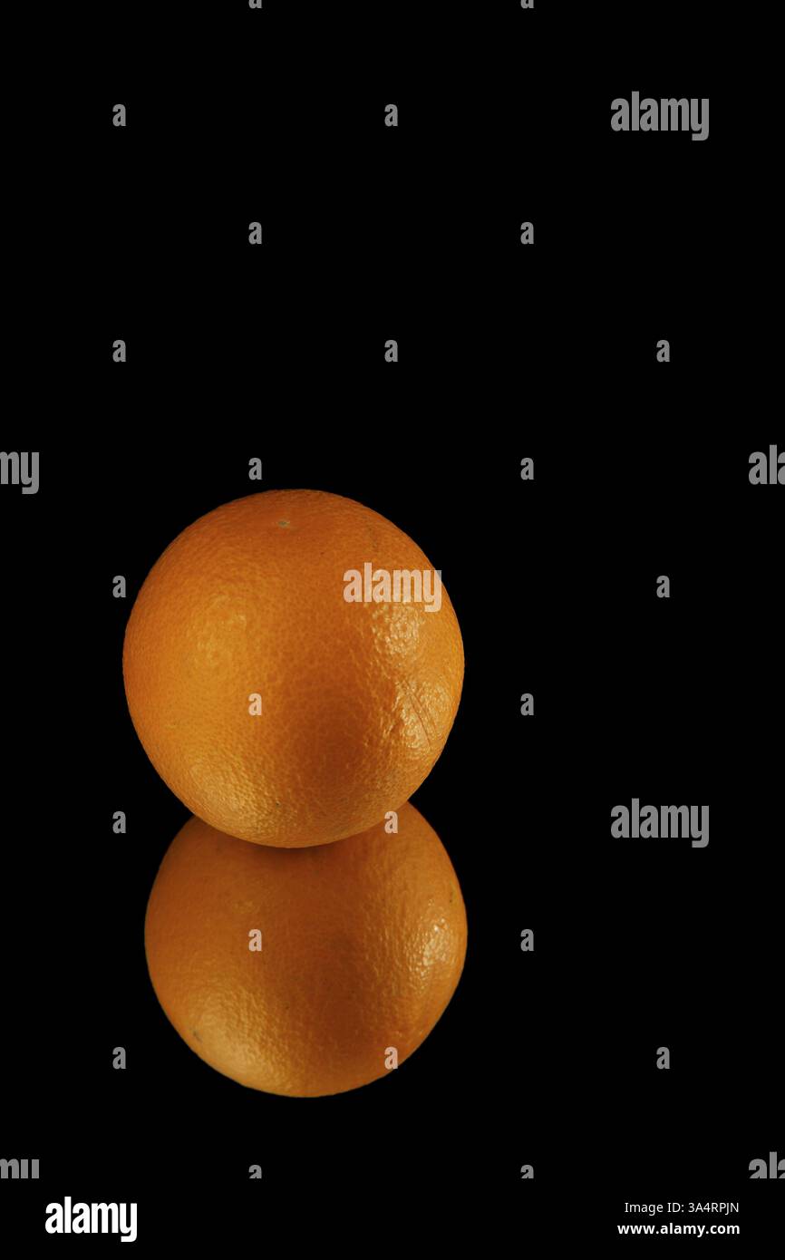 Tutto l'arancione si riflette in uno specchio isolato su sfondo nero con spazio di copia Foto Stock