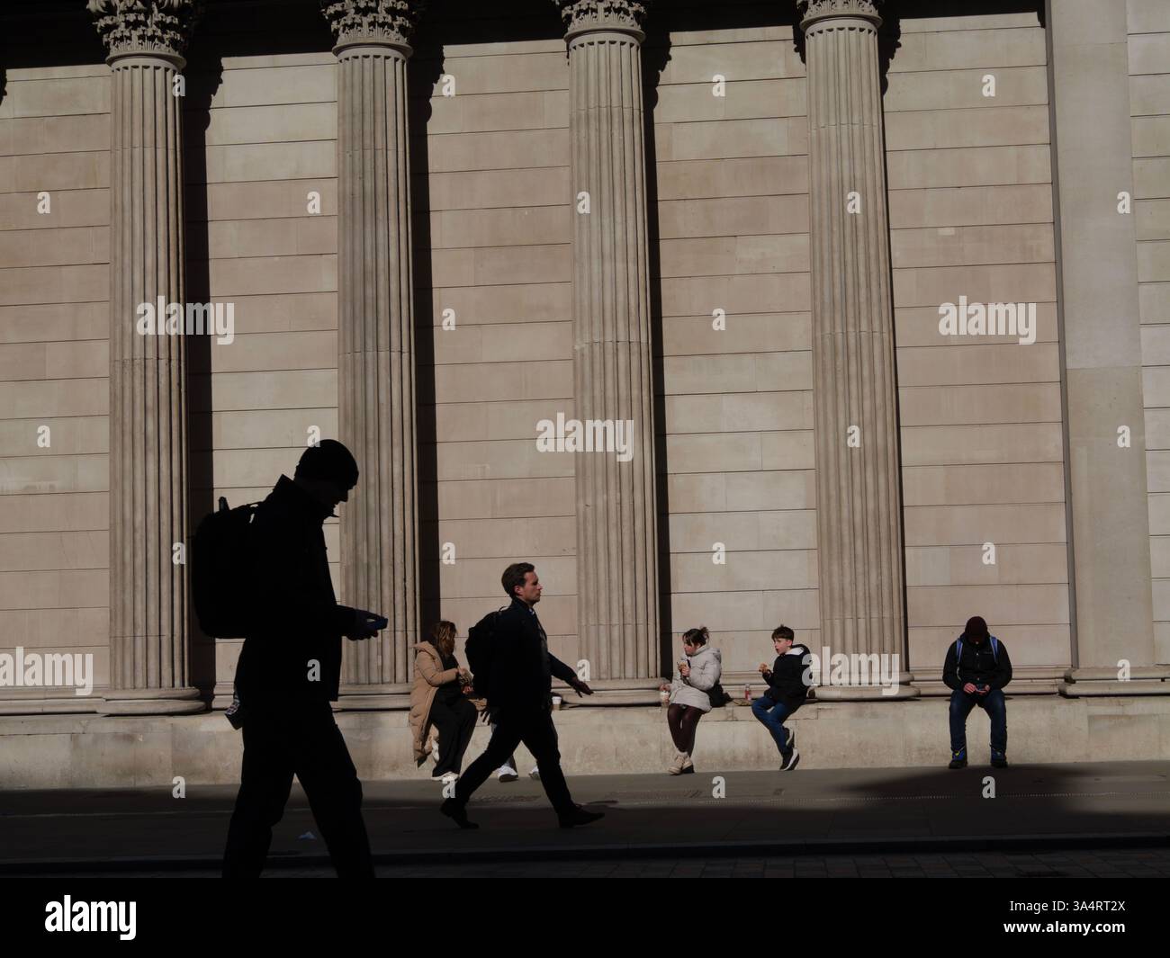 Turisti e lavoratori riposano accanto ai grandi pilastri della Bank of England, Londra, Regno Unito Foto Stock