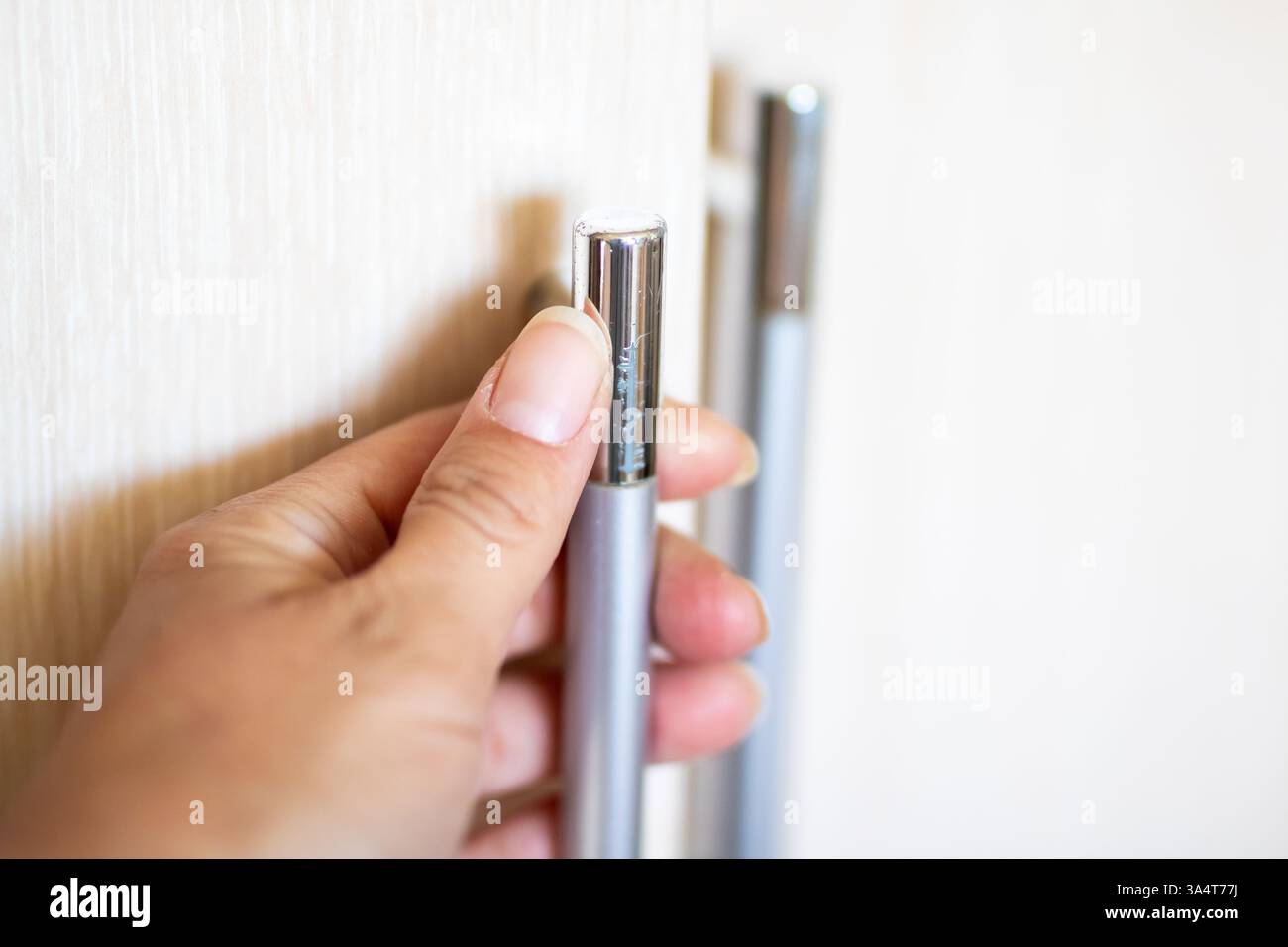 Una persona sta afferrando saldamente una penna in mano mentre la preme contro un muro. La penna è probabilmente realizzata con materiali resistenti Foto Stock