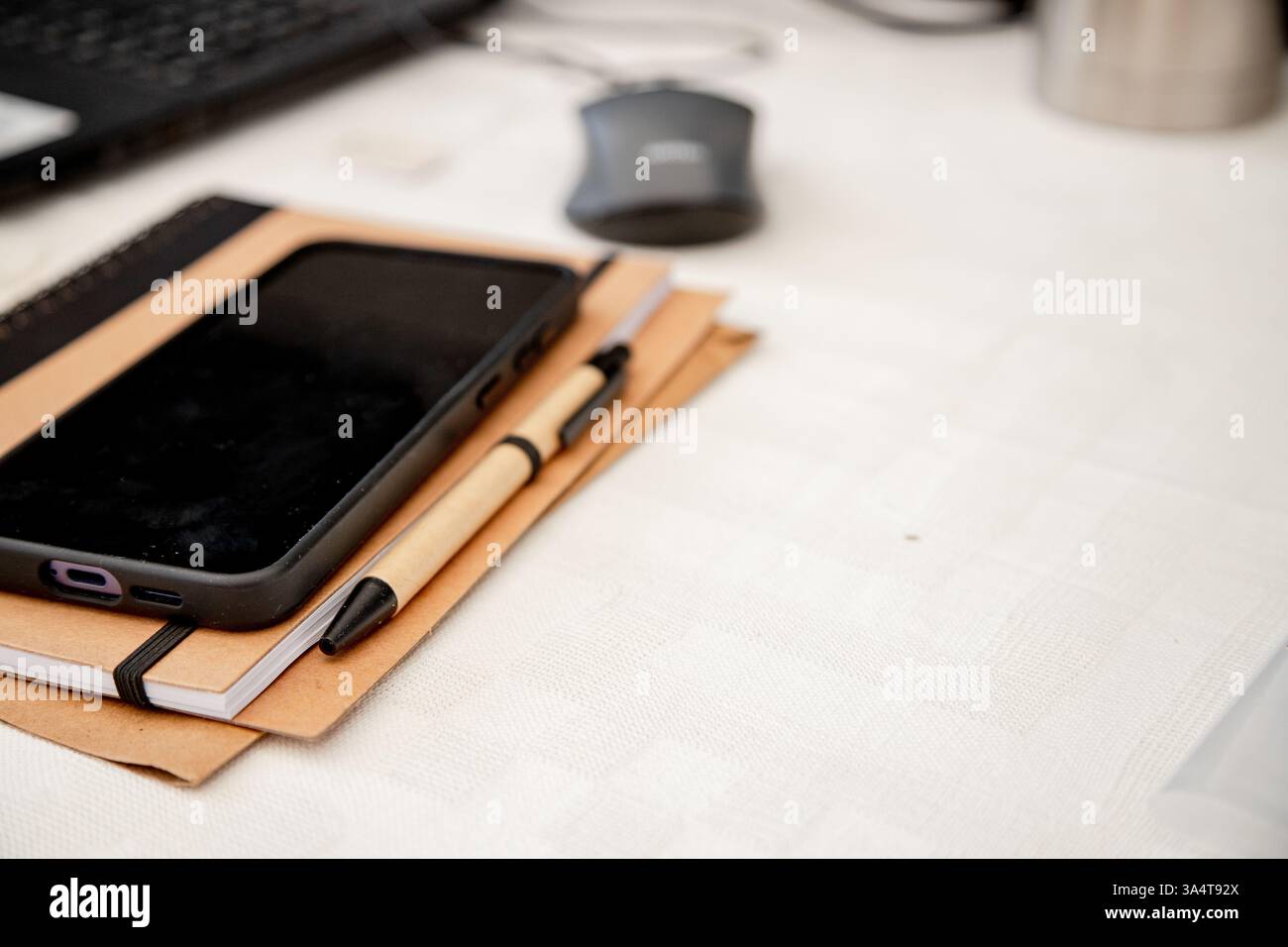 Uno spazio di lavoro ordinato con uno smartphone, un notebook e una penna su una scrivania, pronto per il lavoro o lo studio. Foto Stock