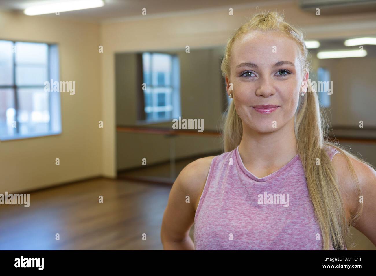 Donna sorridente in studio di danza che indossa canotta rosa, pronta per la pratica, spazio copia Foto Stock Donna sorridente in studio di danza che indossa canotta rosa, pronta per la pratica, spazio copia Foto Stock