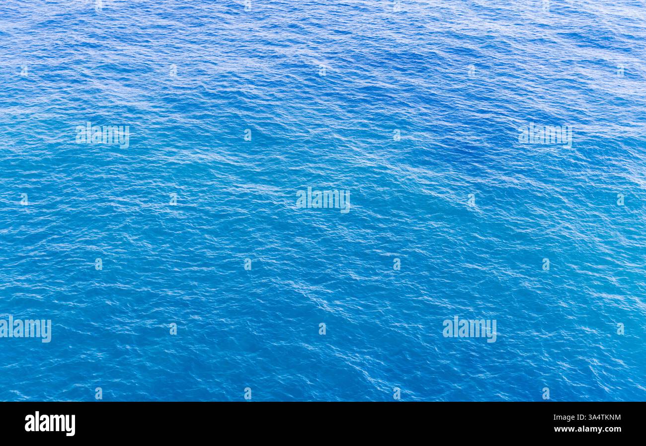 Una vista rilassante della superficie dell'oceano che mostra acqua ondulata in vibranti sfumature di blu sotto la luce del sole, enfatizza il relax, la natura e la tranquillità Foto Stock