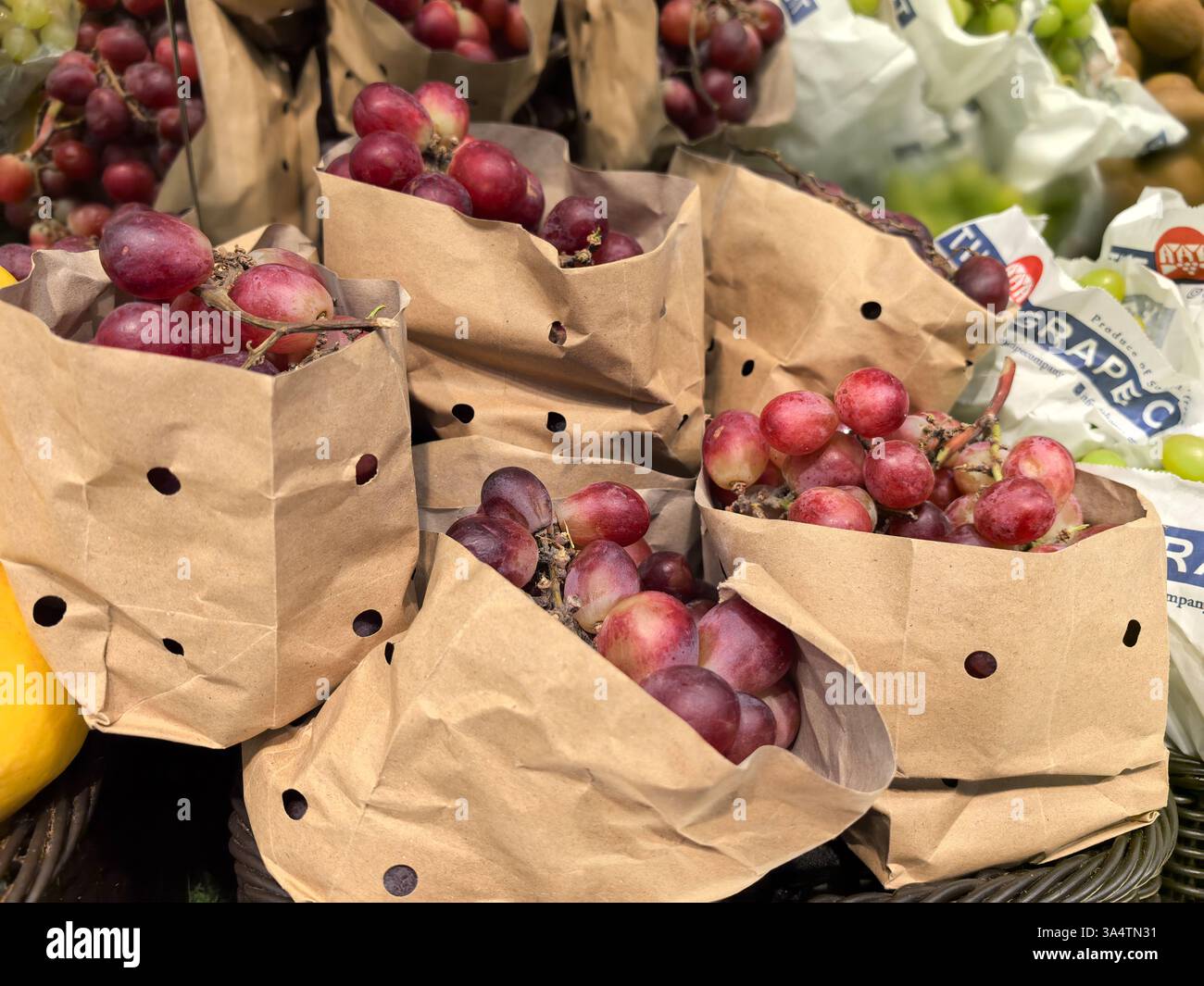 Bobruisk, Bielorussia - 8 marzo 2025: I grappoli di uve succulente sono confezionati in sacchetti di carta ecologici, con una ricca gamma di colori. Foto Stock