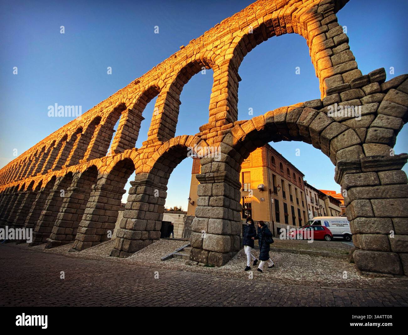 Due persone camminano sotto l'acquedotto romano Acueducto de Segovia a Castilla y Leon, Spagna - Immagine stock catturata con smartphone